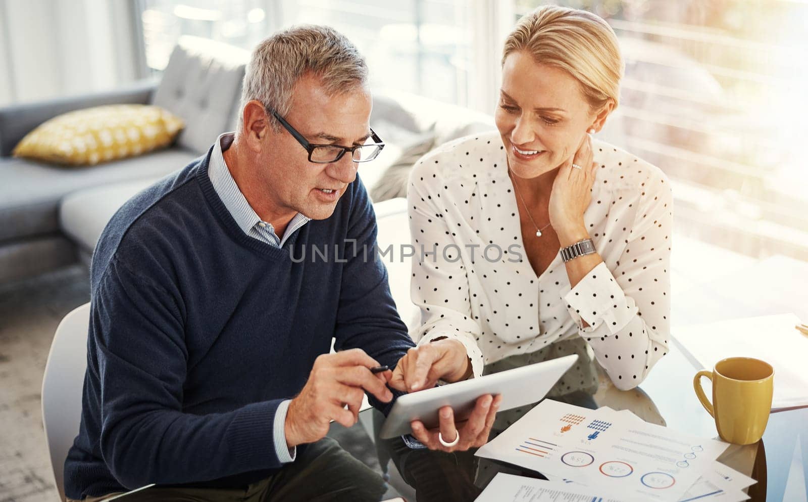 Digital technology is their monthly budget manager. a mature couple using a digital tablet while going through paperwork at home. by YuriArcurs