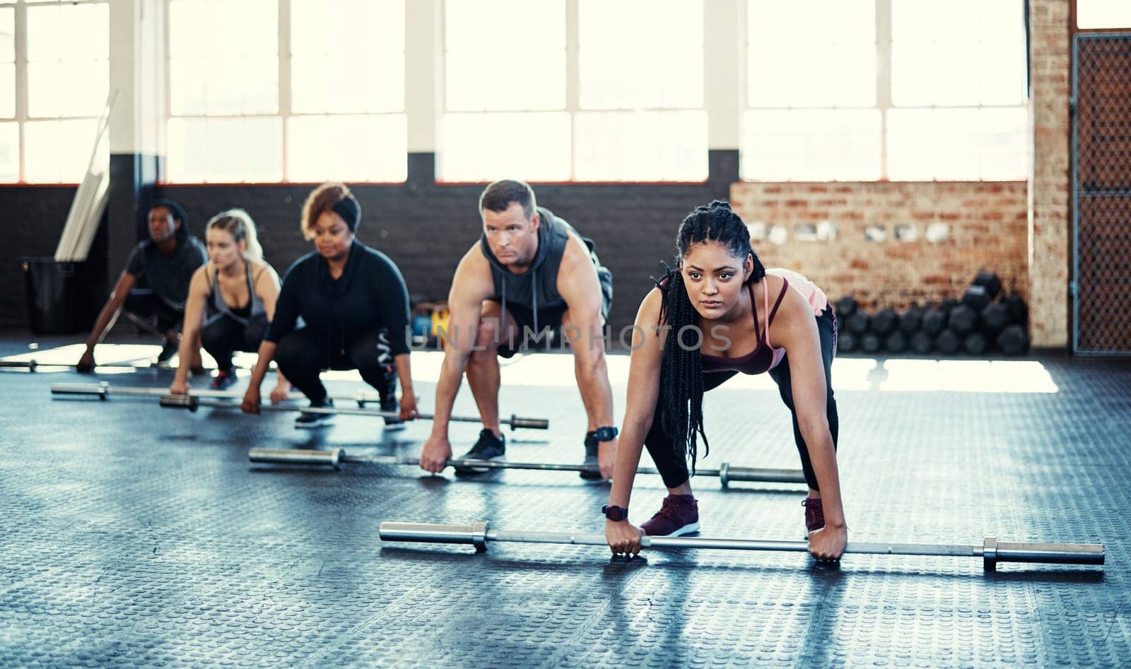 Its your bar, raise it as high as you can. a fitness group using steel bars in their session at the gym