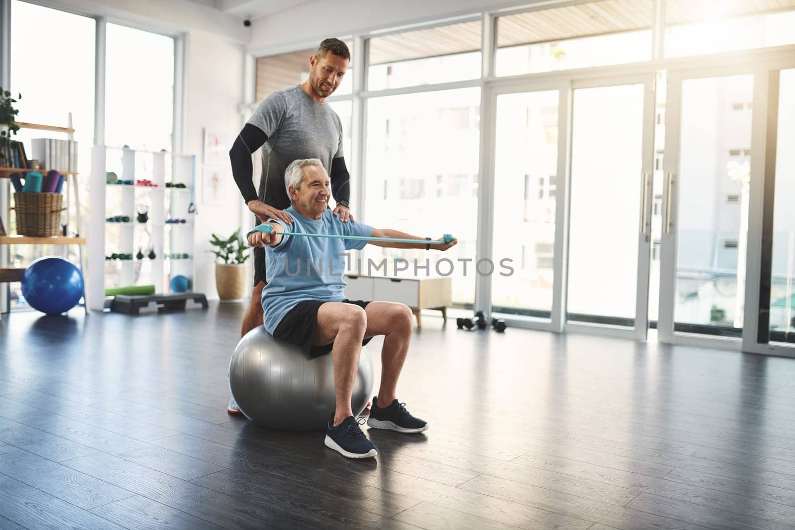 Bring exercise into your life and youll see the results. a young male physiotherapist assisting a senior patient in recovery. by YuriArcurs