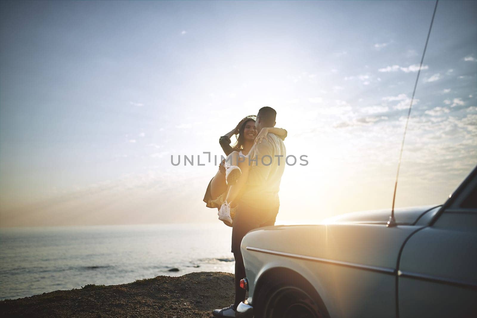 We fell in love where the sky touches the sea. a young couple making a stop at the beach while out on a road trip. by YuriArcurs