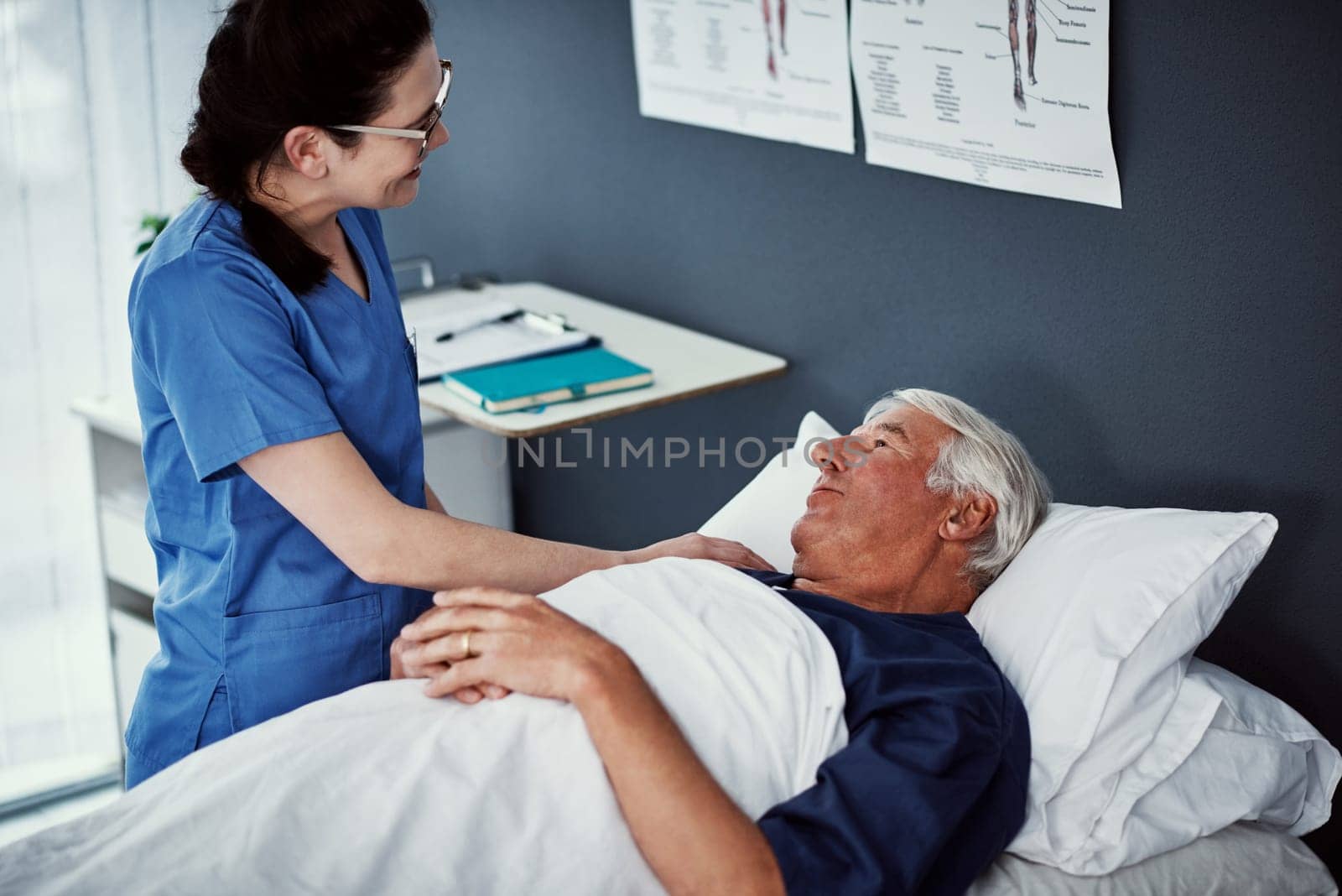 How are you feeling today. High angle shot of a female carer assisting her male patient in a nursing home. by YuriArcurs