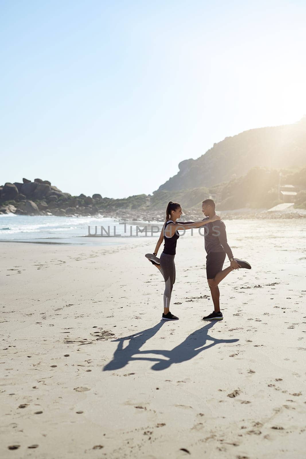 I know I can always lean on you for support. a sporty young couple stretching while exercising along the beach