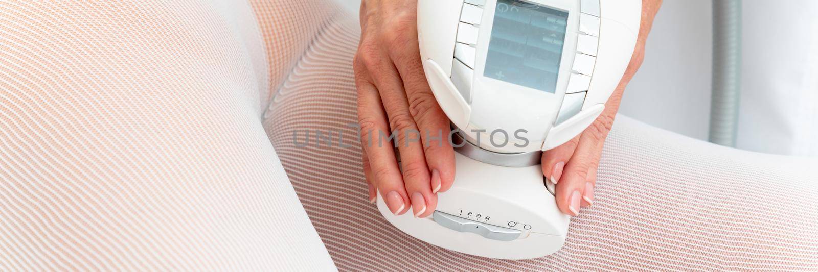 Woman in special white suit getting anti cellulite massage in a spa salon. LPG, and body contouring treatment in clinic