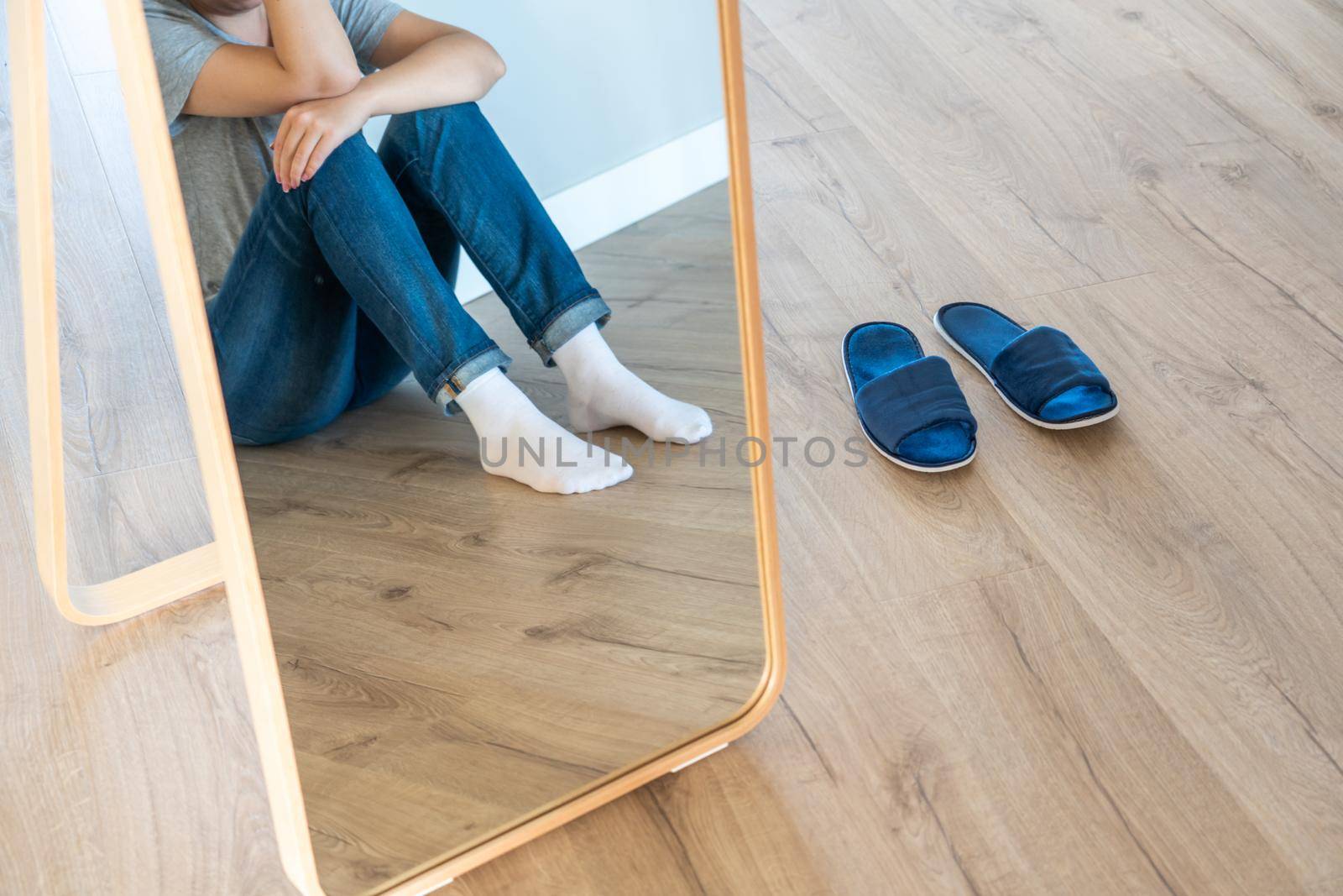 Sad woman sitting on a floor alone in empty room, despair and lonely
