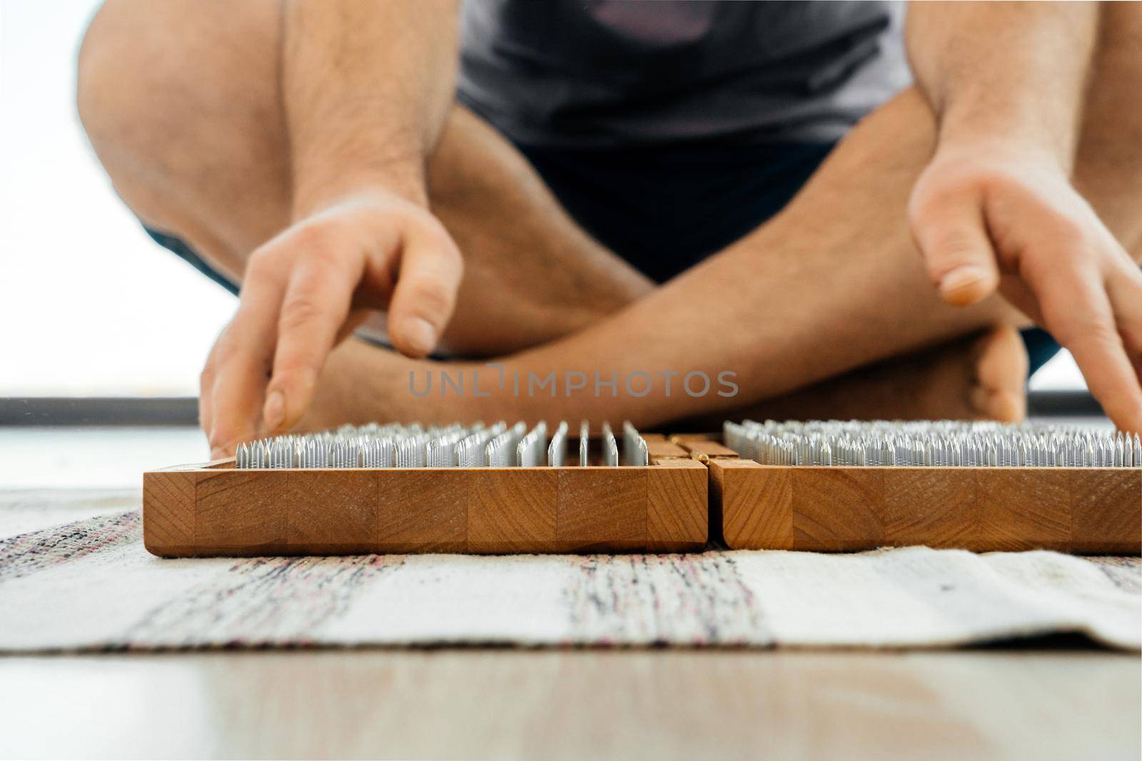 Man exercising yoga meditating and sitting on the floor near sadhu board