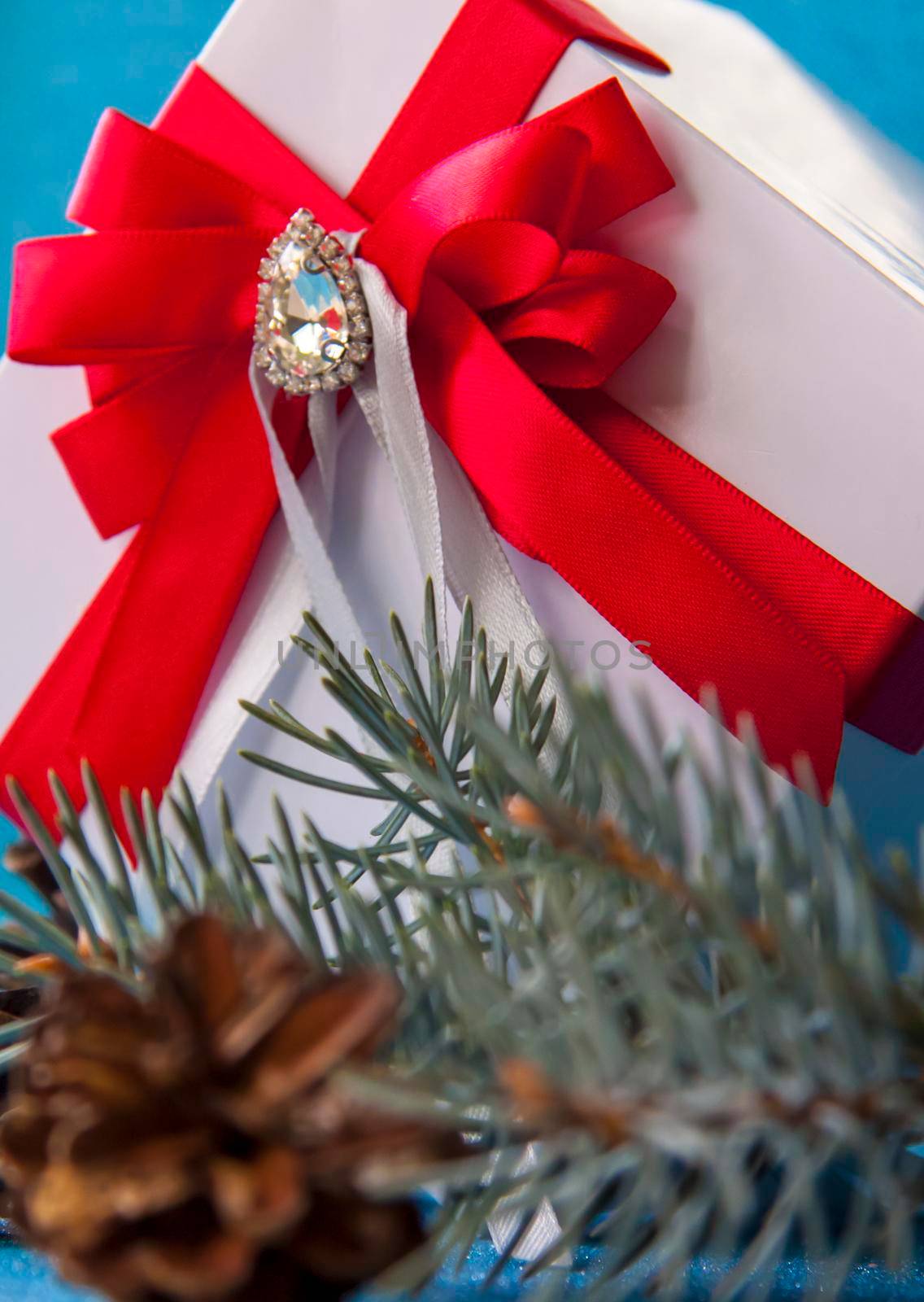 Gift box, spruce branch and fir cone on a bright shiny background. Blue background with sequins.