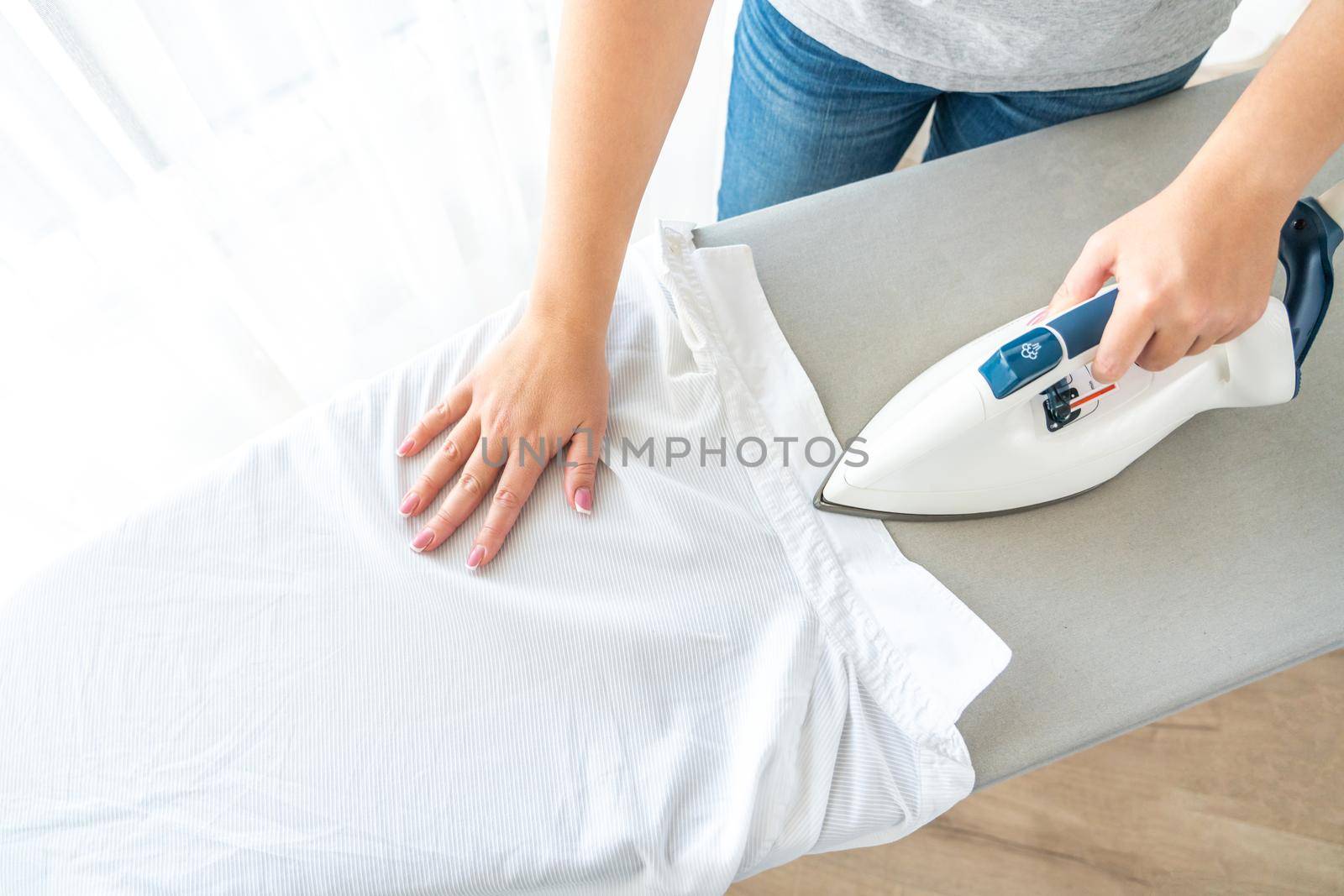 Close up of Female hands ironing white shirt on ironing board