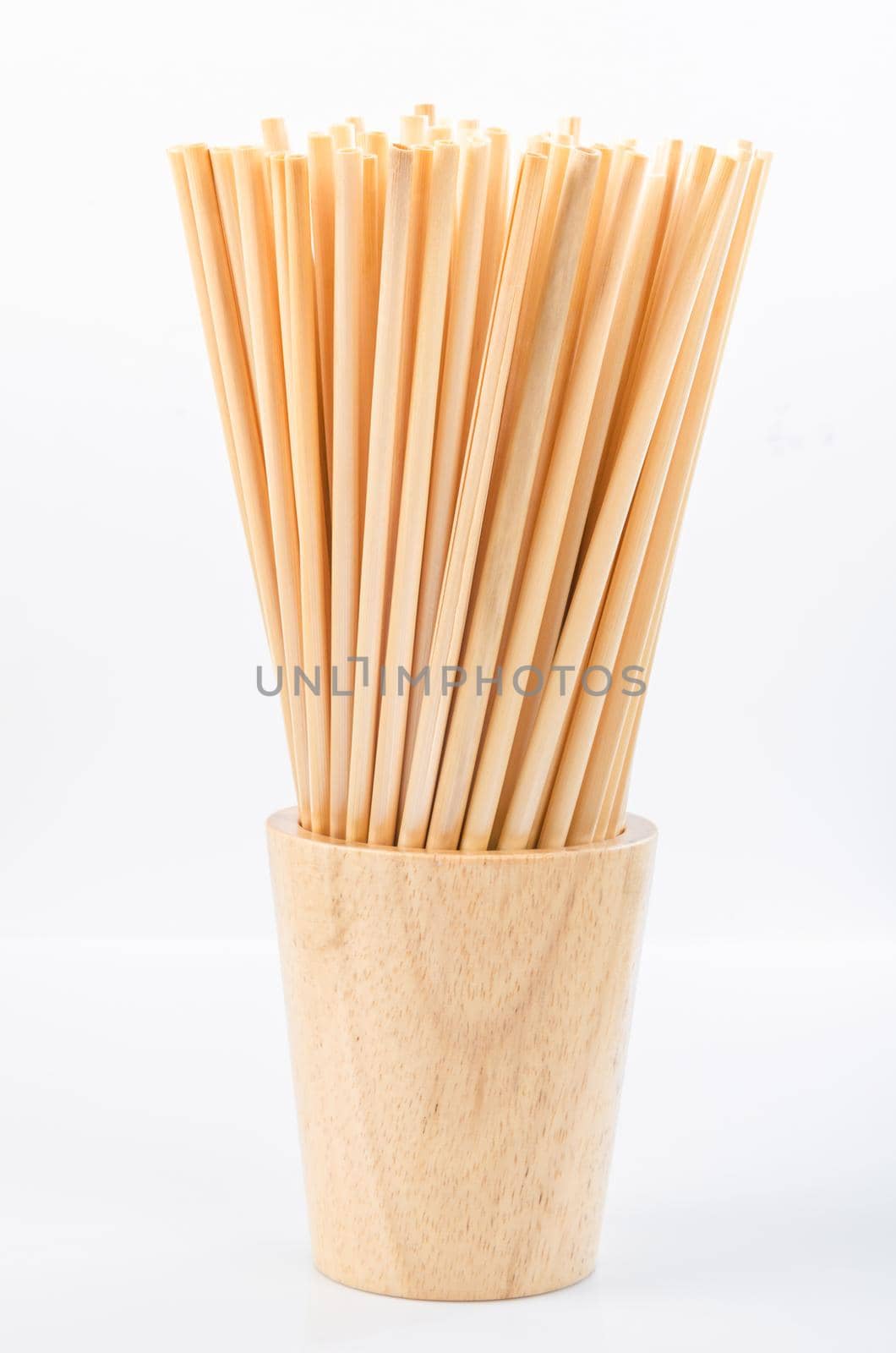 Wheat straw for drinking water in wooden glass on white background. Zero waste concept.