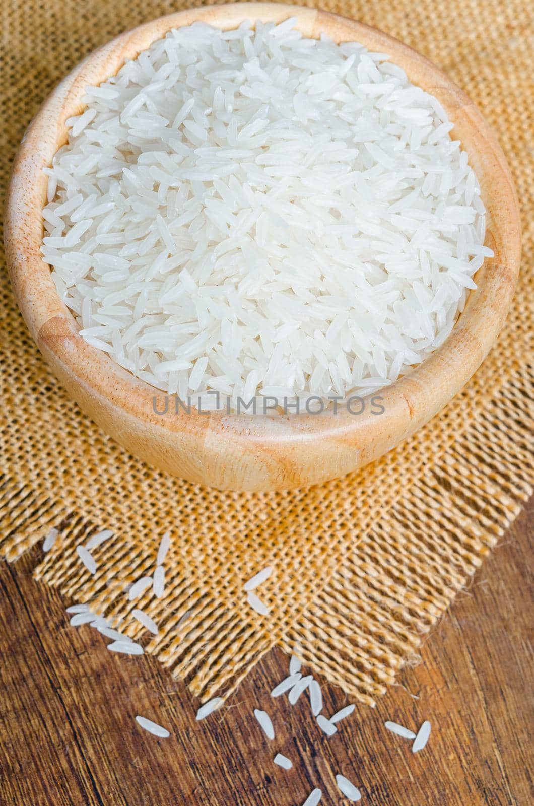 Organic Thai Jasmine rice grain in wooden bowl. by Gamjai