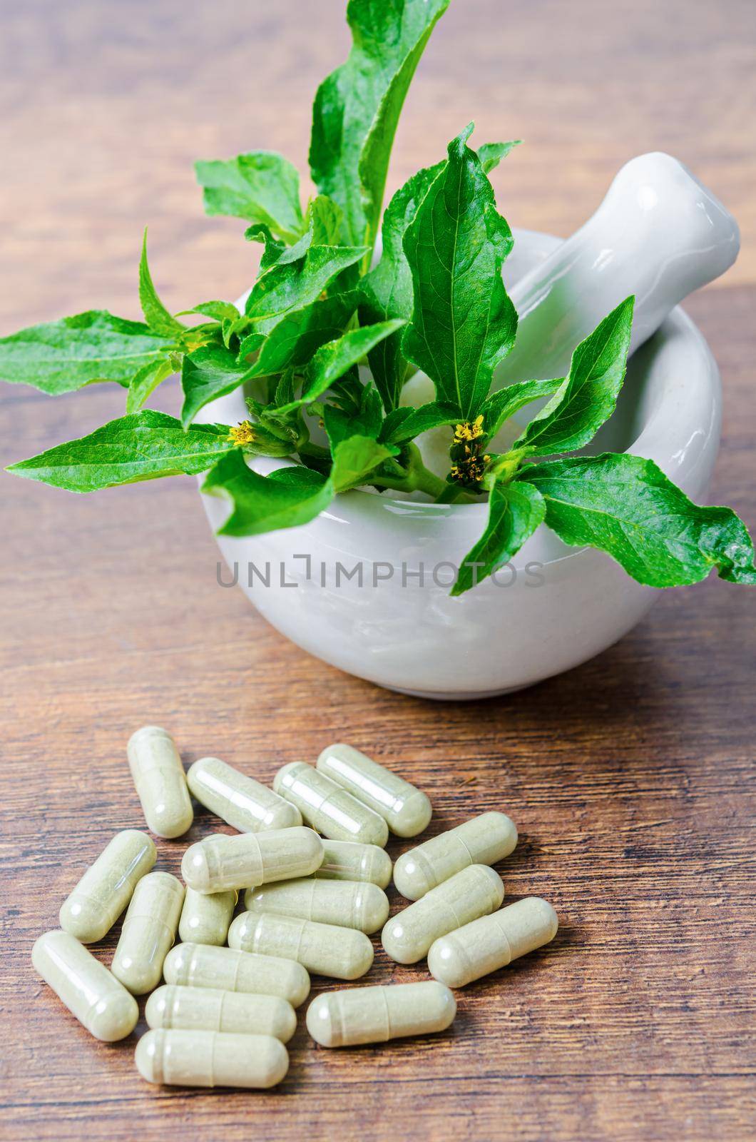 Pile of herbal medicine in capsules and ceramic mortar. by Gamjai