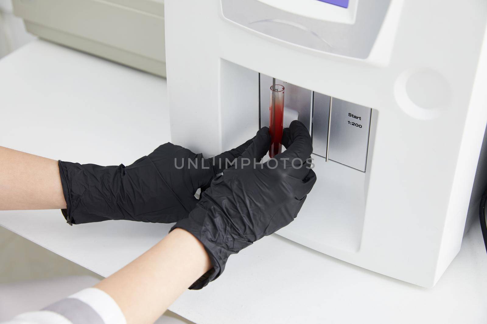Female Research Scientist Putting Test Tube with Blood Sample into Analyzer Medical Machine. Scientist Works with Modern Medical Equipment in Pharmaceutical Laboratory