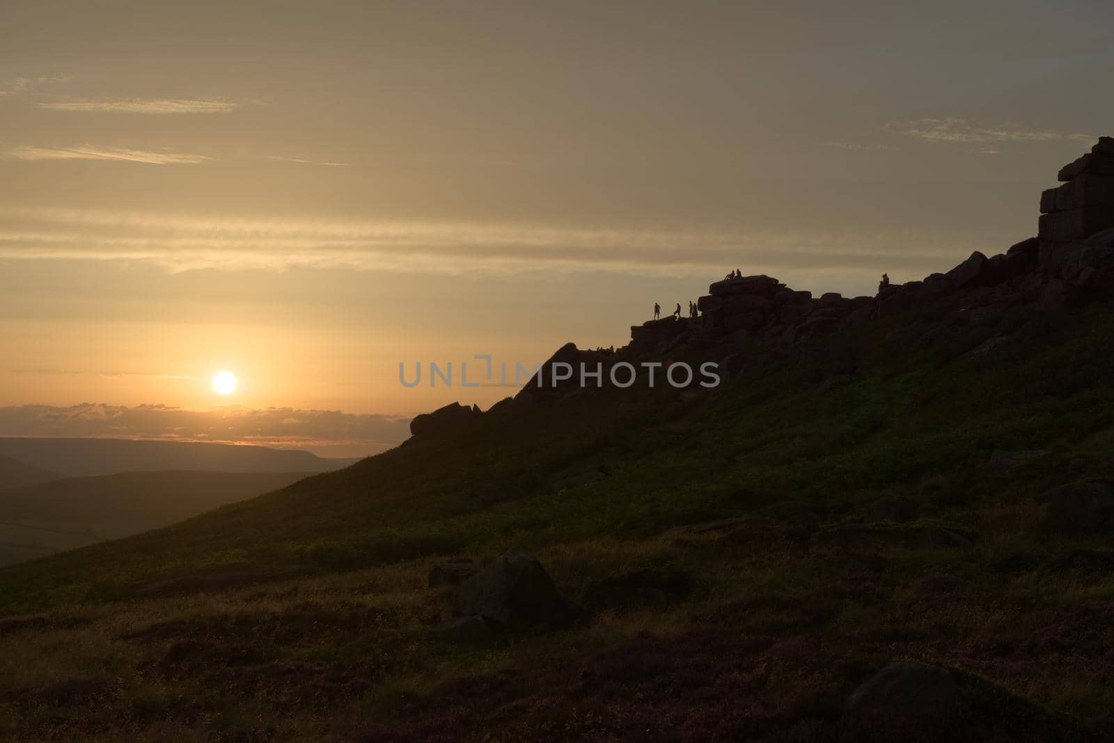 Wide angle sunset at stanage edge. Many people pursue outdoor recreational activities on top of the rocky edge. Dramatic and popular landmark