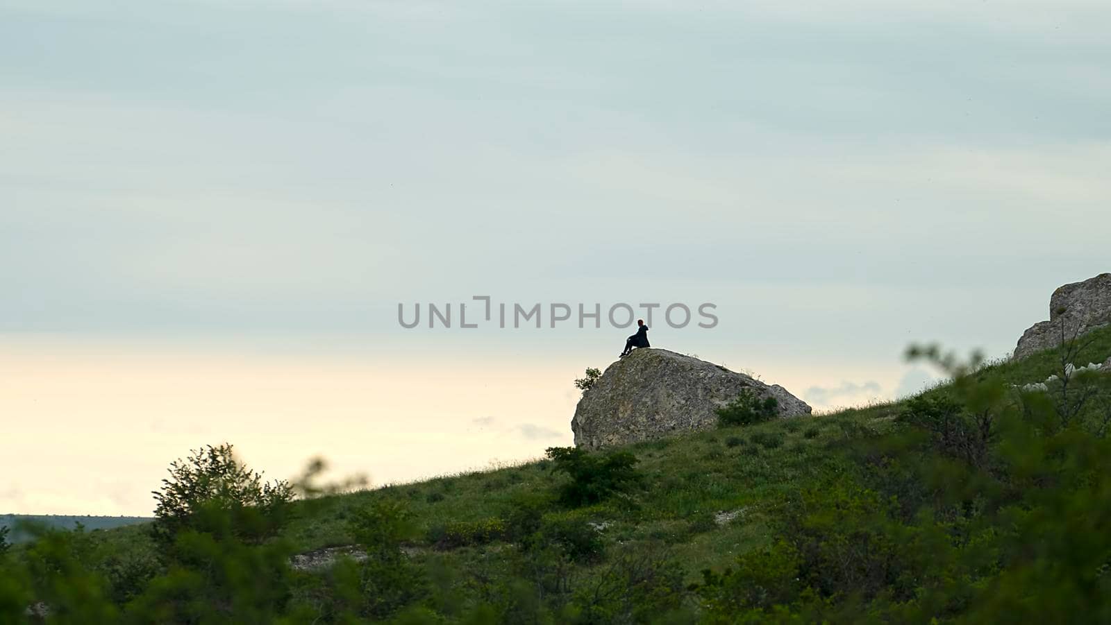 Landscape with the figure of a man on a large stone by Vvicca