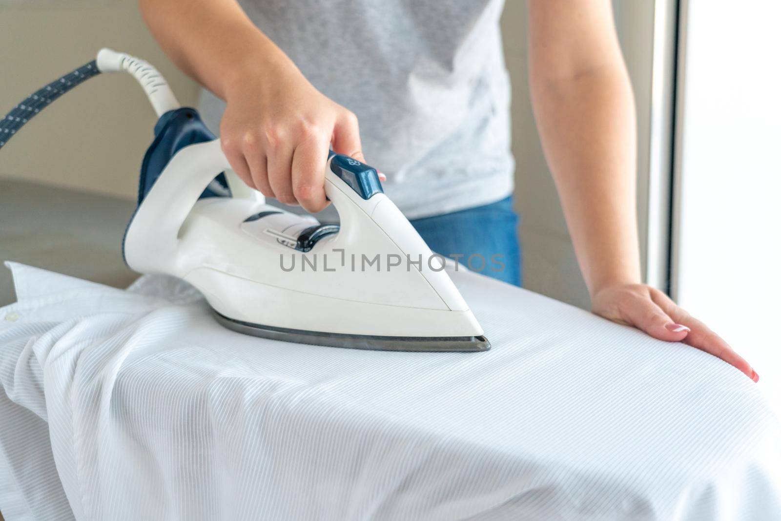 Close up of Female hands ironing white shirt on ironing board