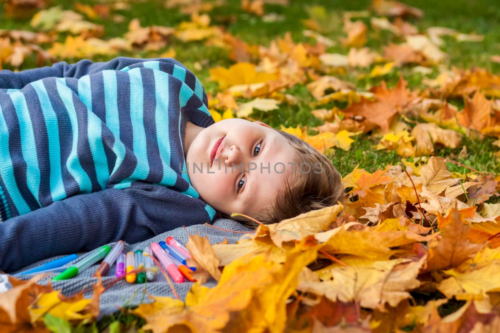 Autumn mood. The boy is thoughtfully drawing something in his notebook.Autumn portrait of a child in yellow foliage. Sight. A sweet, caring boy. Autumn