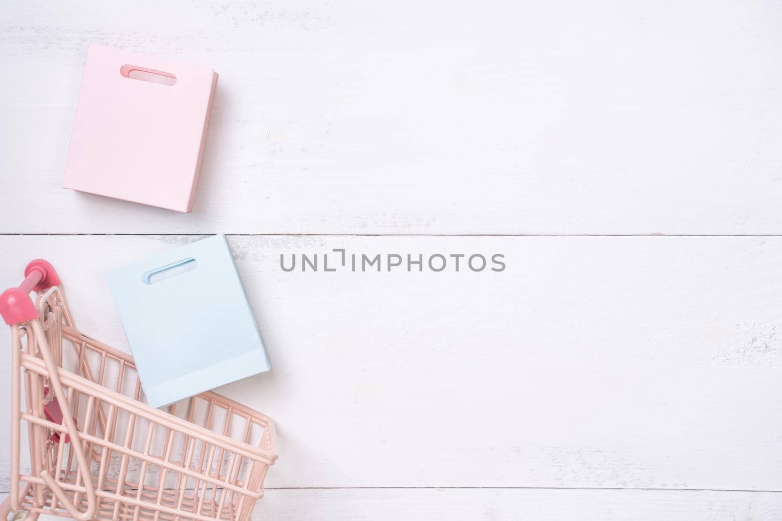 Abstract design element,annual sale,shopping season concept,mini cart with colorful paper bag on white wooden table background,top view,flat lay