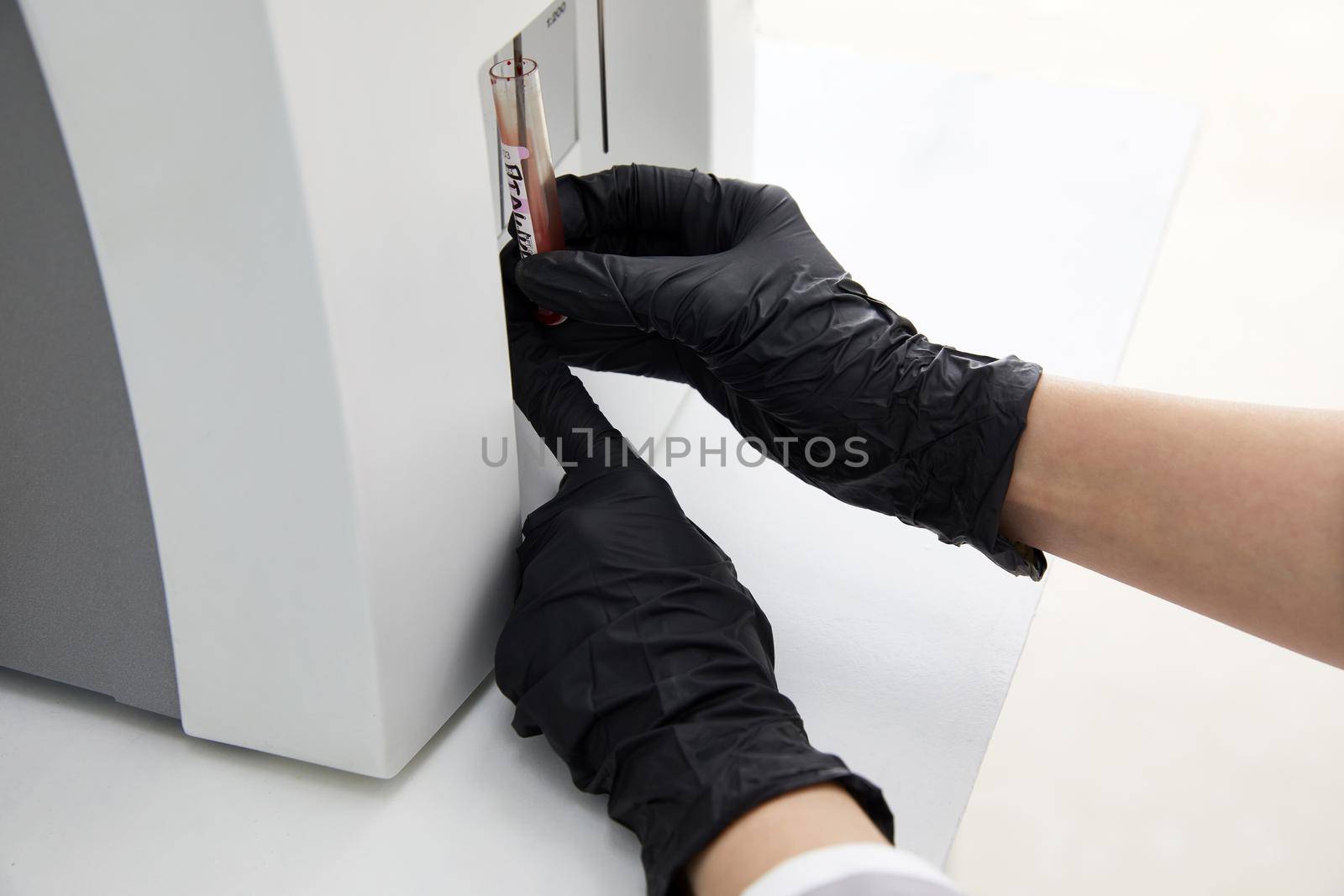 Female Research Scientist Putting Test Tube with Blood Sample into Analyzer Medical Machine. Scientist Works with Modern Medical Equipment in Pharmaceutical Laboratory