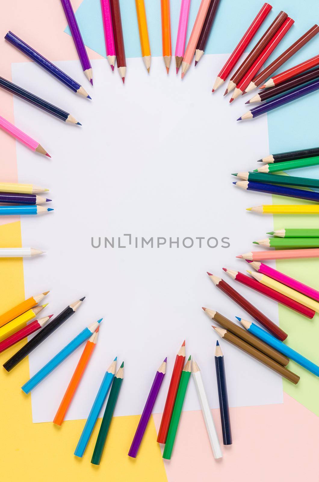 Many colored wooden pencils on paper with copy space for your text or message.