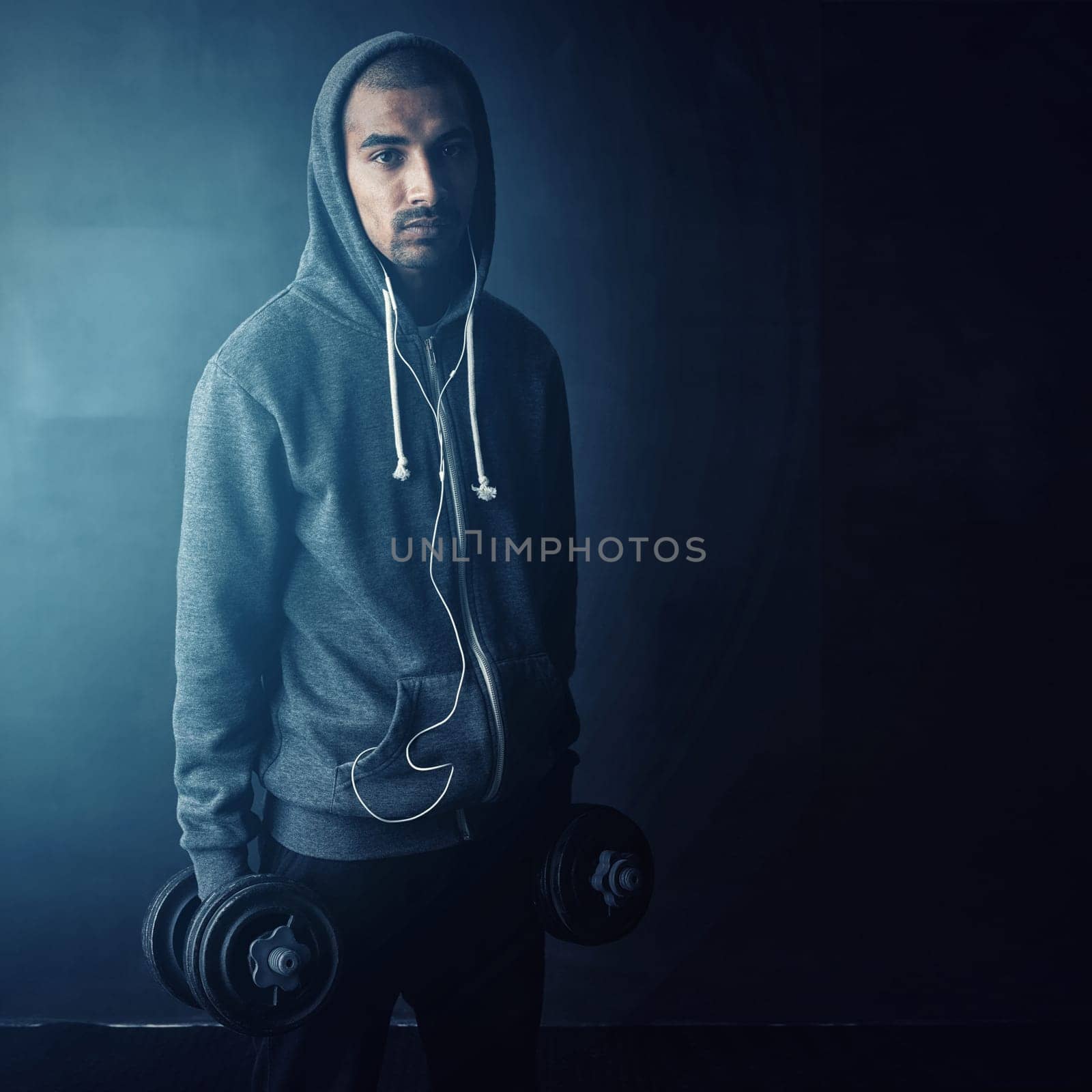 I stay strong. Studio portrait of a young man working out against a dark background. by YuriArcurs