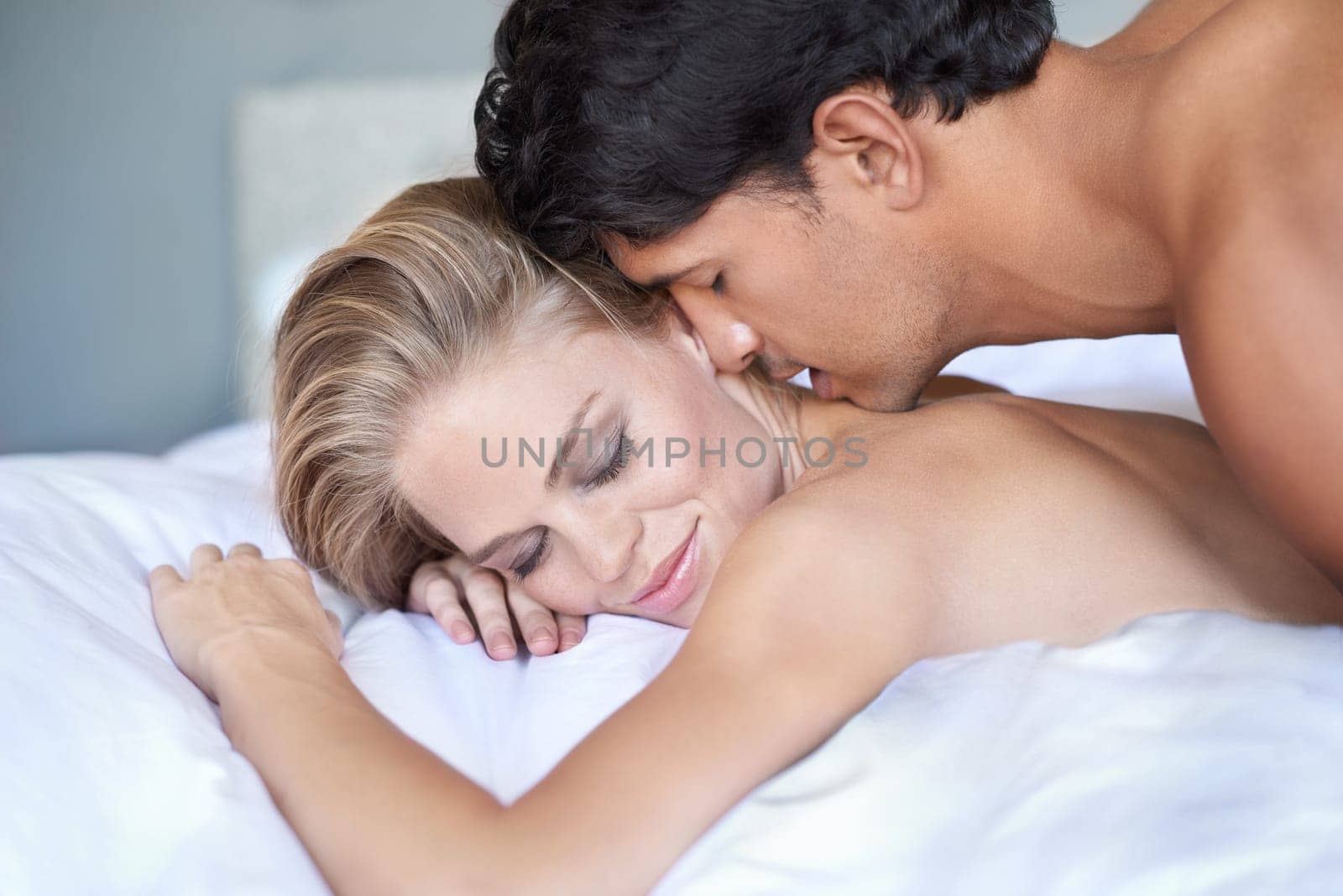 The best way to be woken up. A handsome young man kissing his girlfriend on her bare back