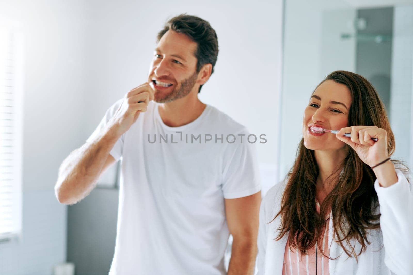 Getting ready for the day ahead together. a couple brushing their teeth in the bathroom at home together. by YuriArcurs