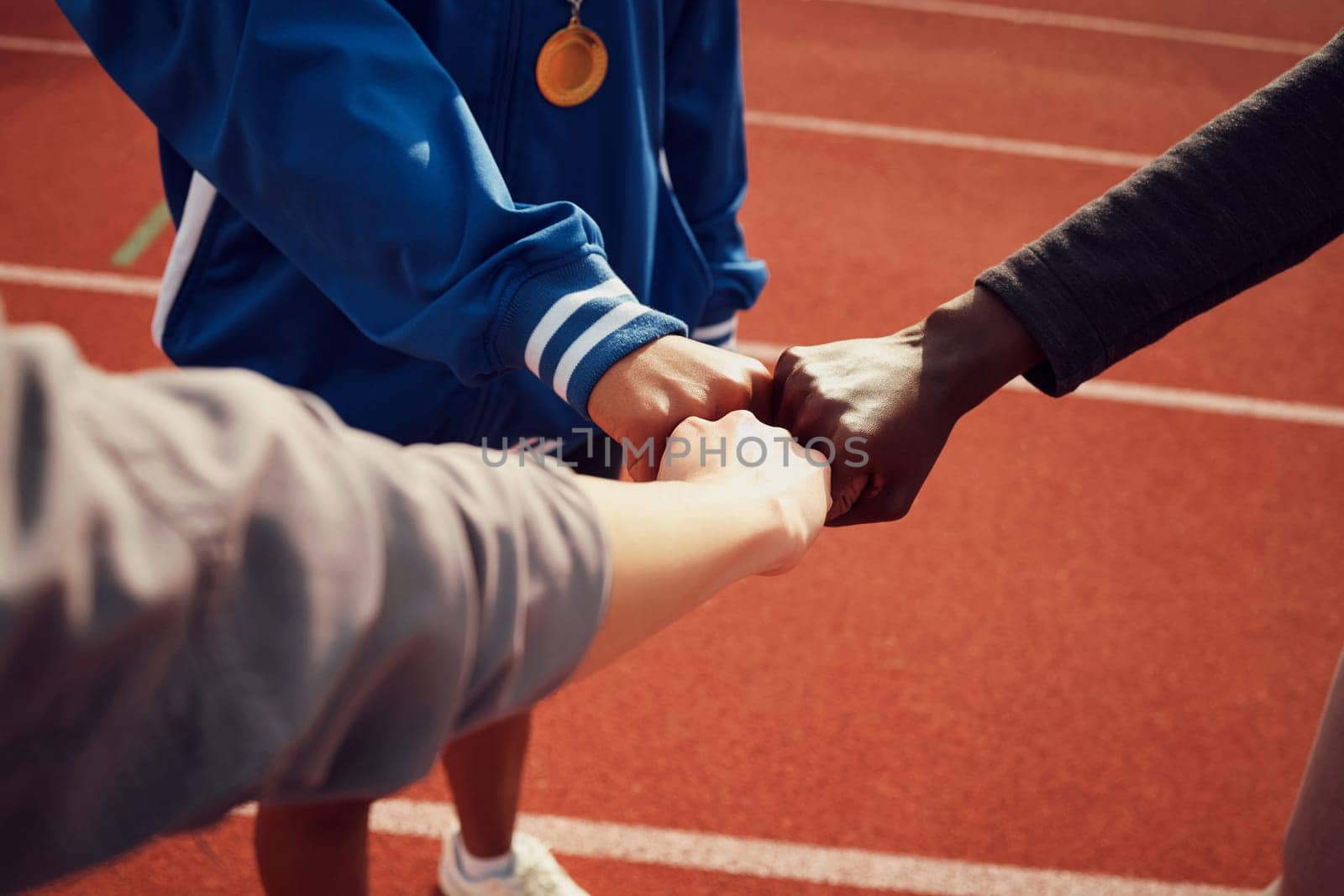 People, diversity and fist bump in fitness for unity, trust or support together on stadium track. Hands of group touching fists in team building for sports motivation, teamwork or goals outdoors.