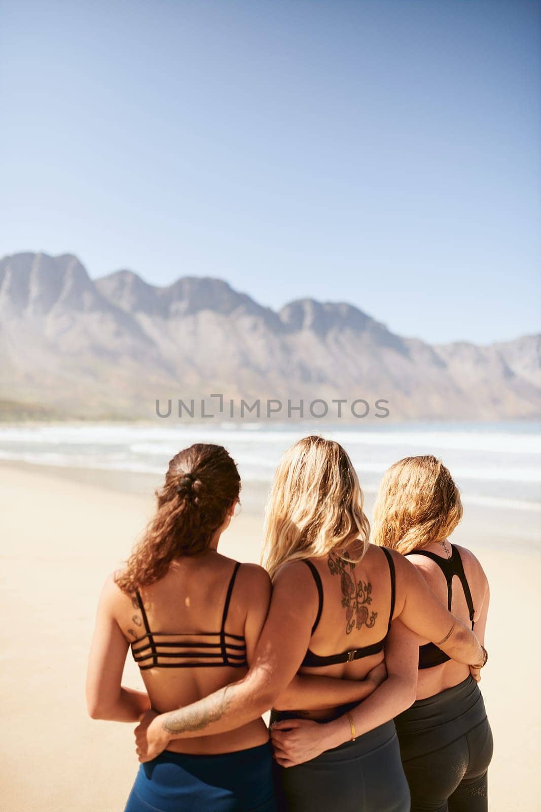 Yoga has taught us so much. Rearview shot of three young yogis standing on the beach. by YuriArcurs