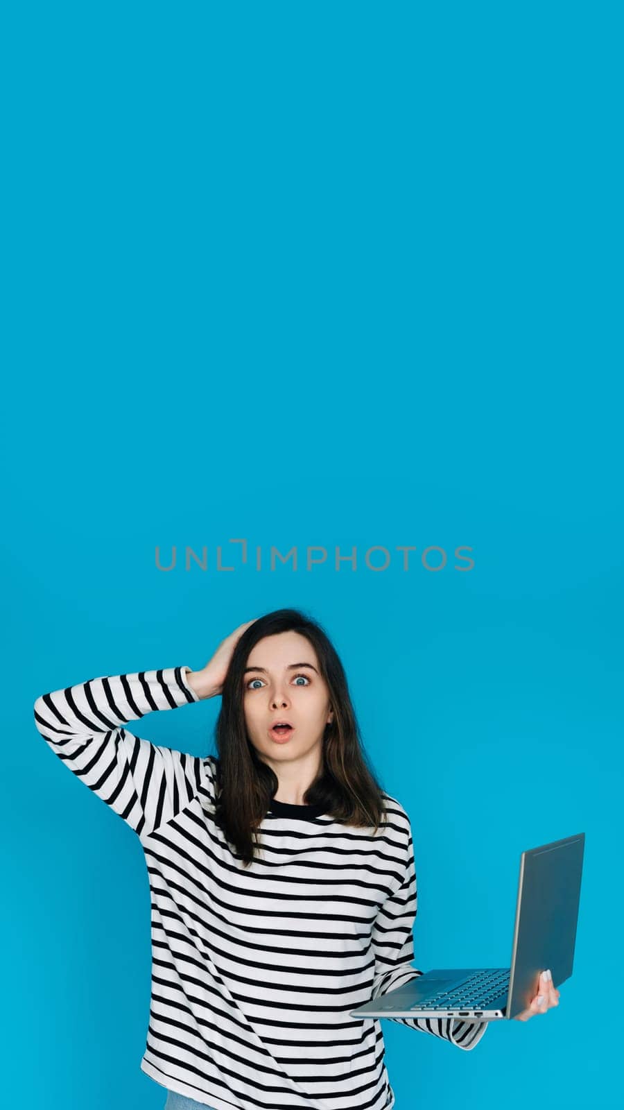 Emotional Woman in Striped Sweater Reacting to Bad News on Laptop - Conceptual Image of Sadness, Disappointment, and Technology - Isolated Blue Background with Copy Space - Perfect for Emotional,