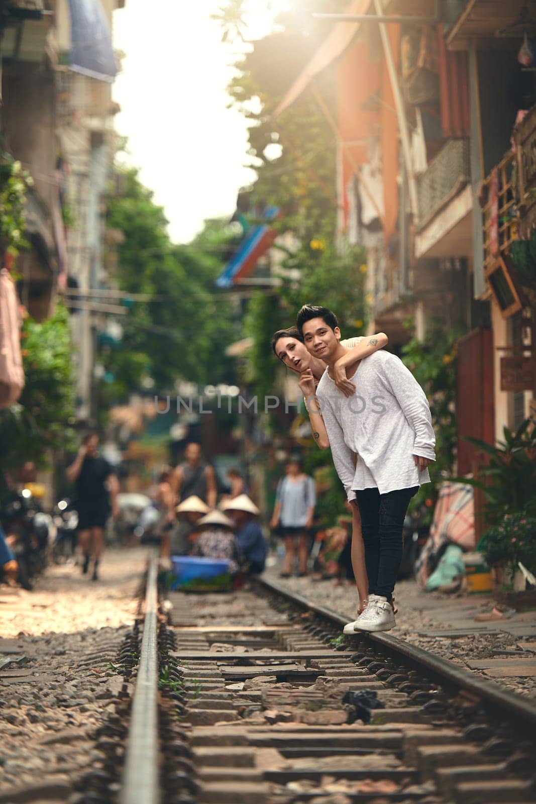 Next stop, everywhere. a young couple waiting for their train to arrive while exploring Vietnam. by YuriArcurs