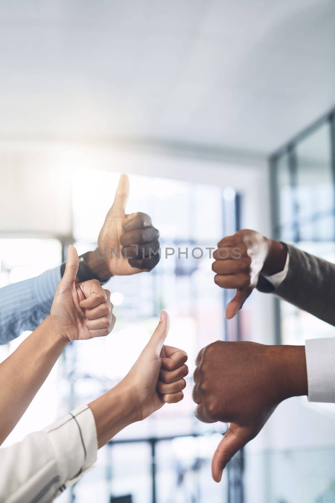 Lets put it to a vote. Closeup shot of a group of businesspeople showing thumbs up and down in an office