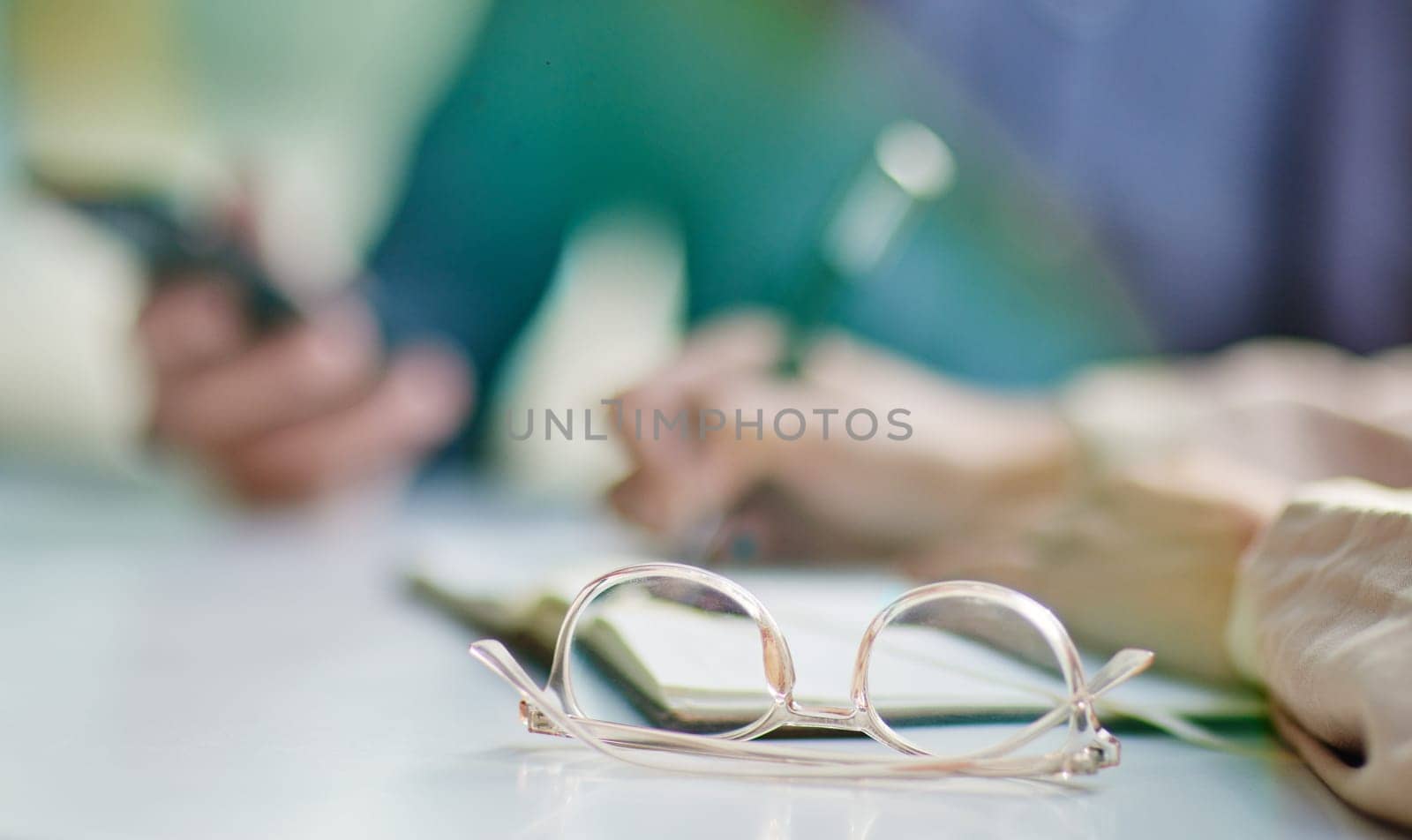 Glasses on desk, vision and eye care with business people in meeting, writing in notebook with strategy collaboration closeup. Eyewear, prescription lens and notes with ideas, planning with team by YuriArcurs