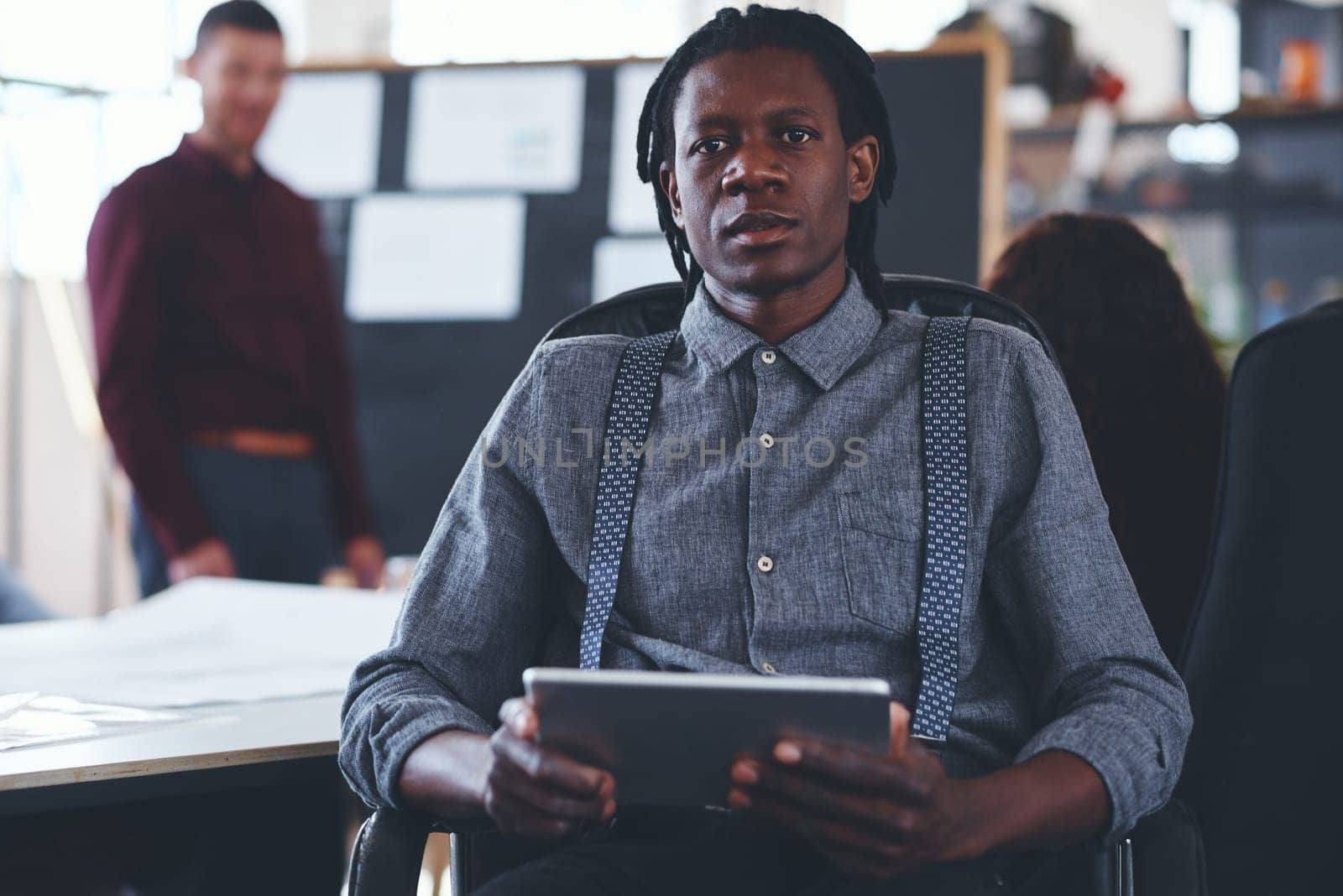 Its where I store all my important notes. Portrait of a young businessman using a digital tablet during a meeting in an office