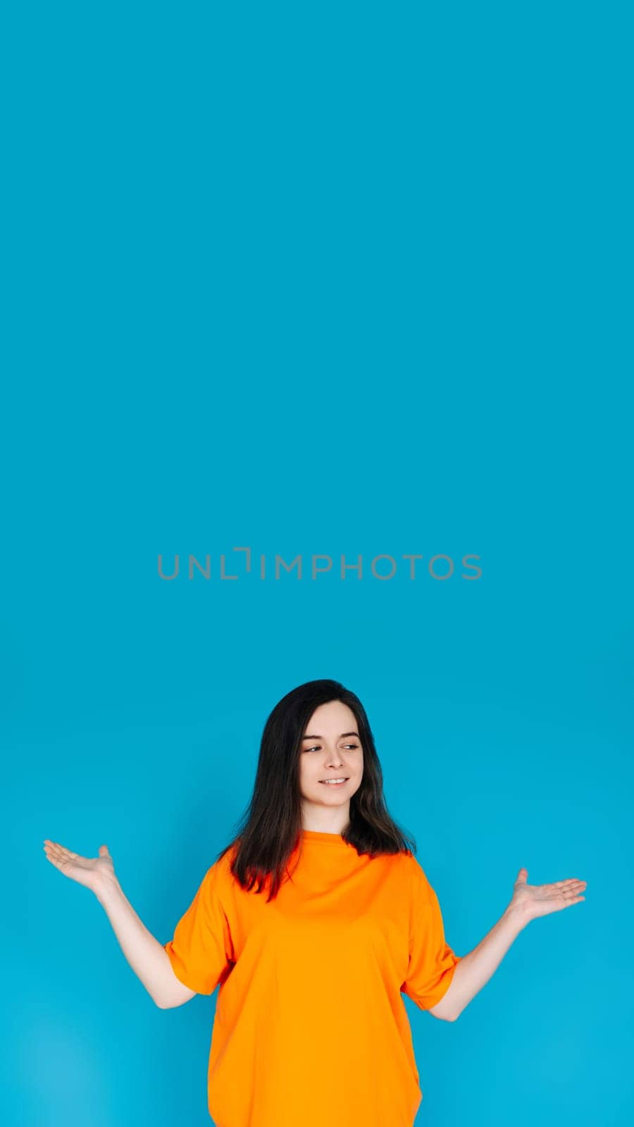 Smiling Young Woman Holding Empty Copy Space in Palms, Attractive Female Model, Isolated on Bright Blue Background, Portrait Photo.