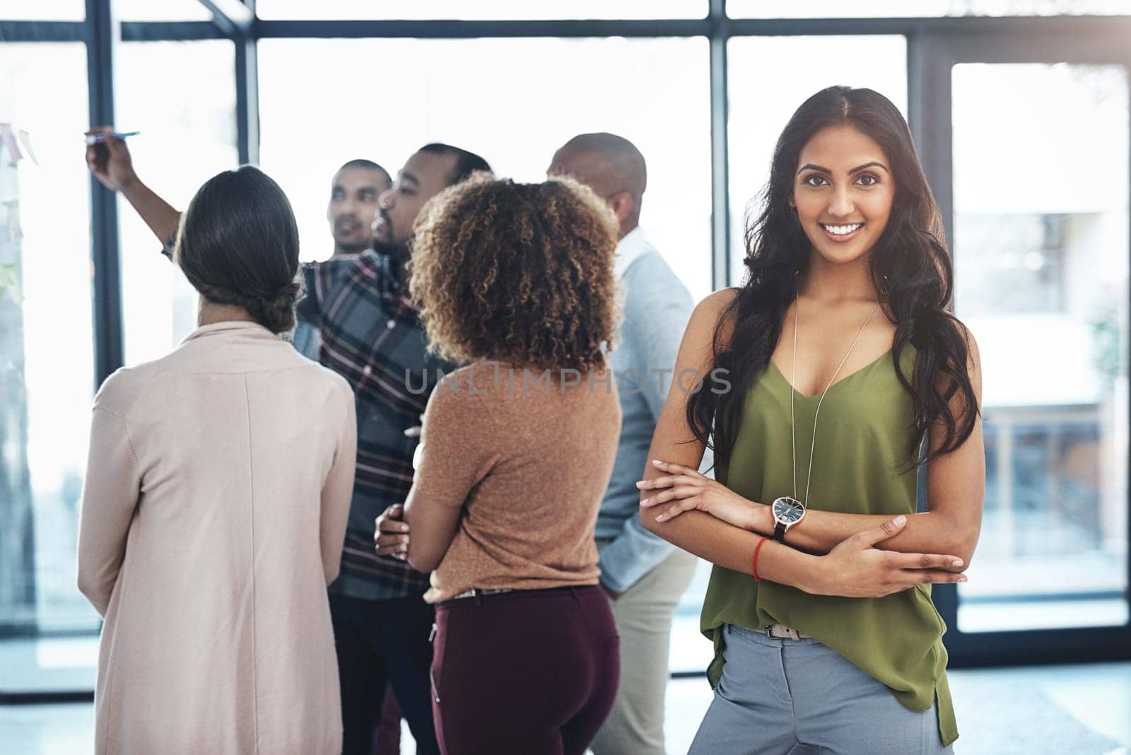 Ive got a great team behind me. Portrait of an attractive young woman standing in the office with her colleagues in the background. by YuriArcurs