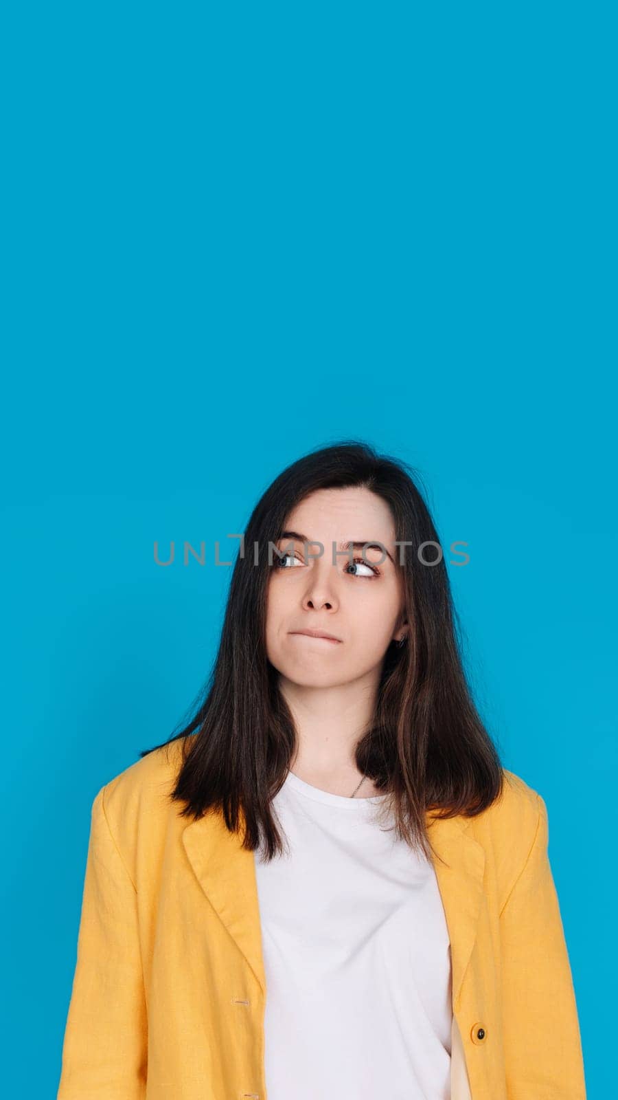 Serene Young Woman Contemplating, Gazing into Empty Space, Thoughtful Young Woman in Captivating Portrait, Lost in Contemplation, Isolated on Blue Background.