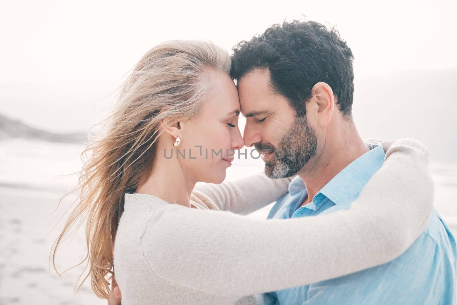 Love, touching face and couple at beach for holiday, vacation and weekend for anniversary. Intimacy, marriage and loving mature man hugging woman for bonding, quality time and romantic trip by ocean.