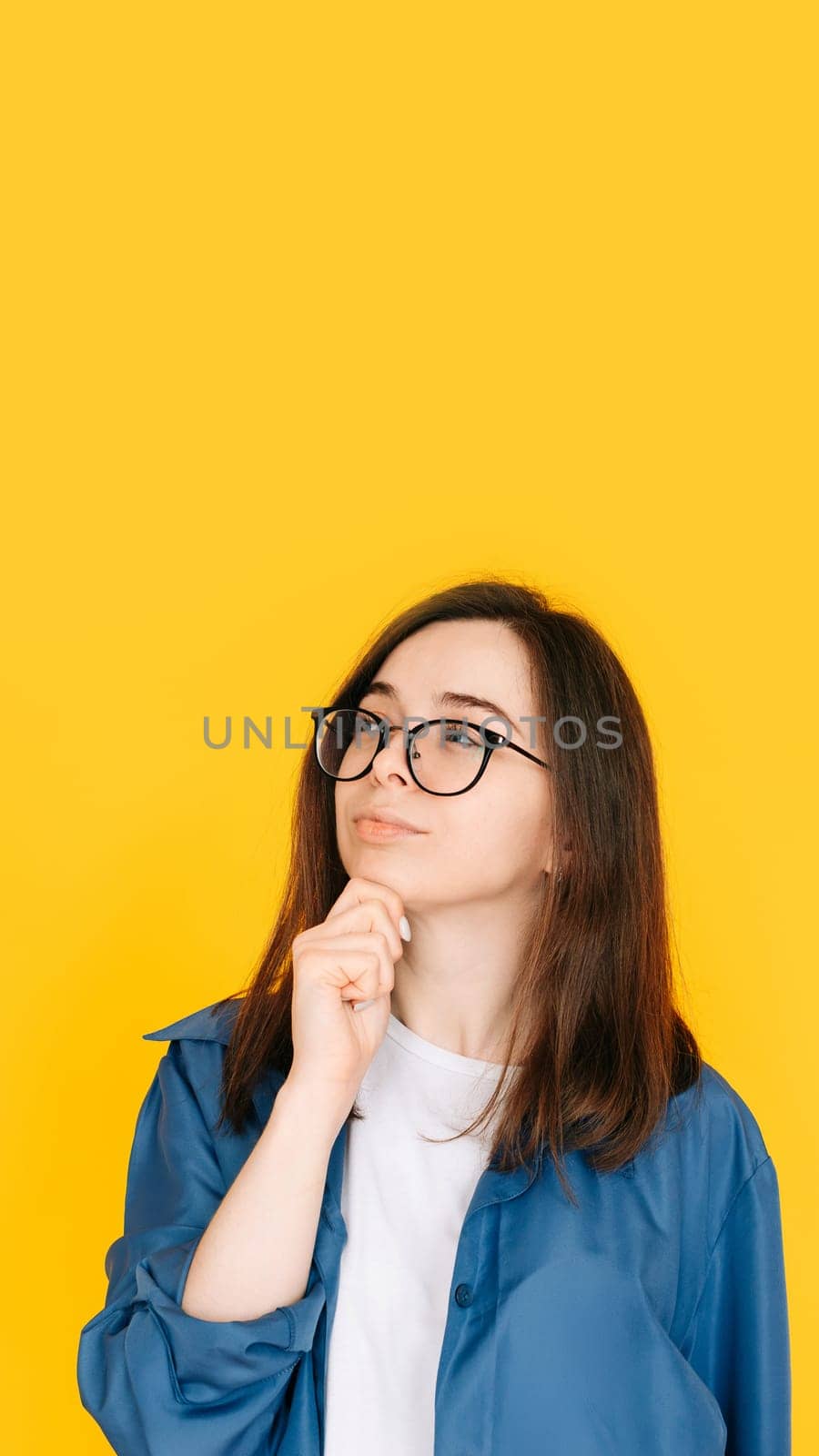 Smart Shopping Decision: Stylish and Thoughtful Woman Considering New Product Purchase, Arm on Face Pose - Fashionable Consumer Concept Isolated on Yellow Background by ViShark