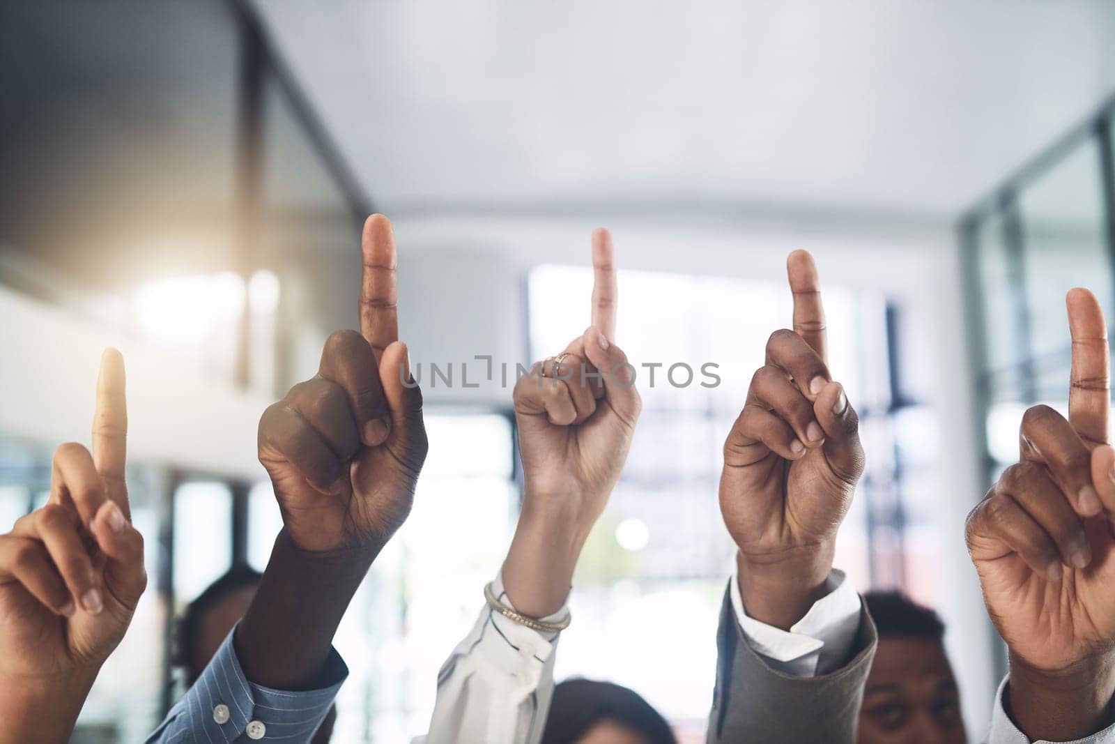 Just a quick question...Closeup shot of a group of businesspeople raising their hands in an office