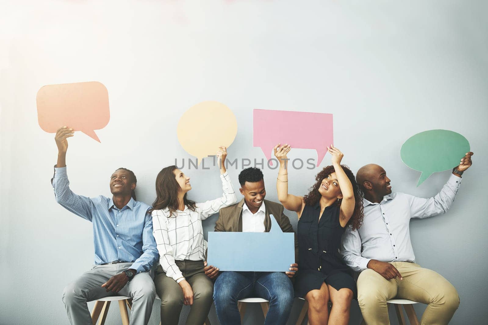 Have your say. Studio shot of a group of businesspeople holding colorful speech bubbles in line against a gray background