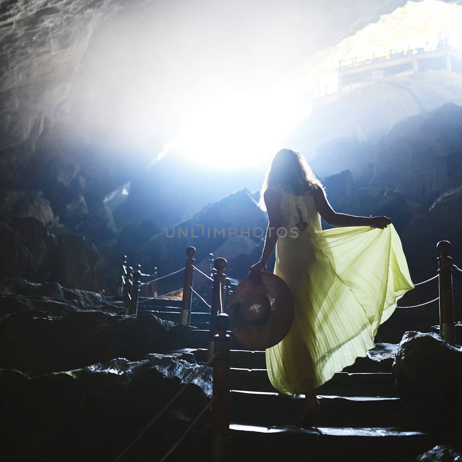 In darkness, let your soul light the way. a young woman walking up steps in a Vietnamese cave. by YuriArcurs