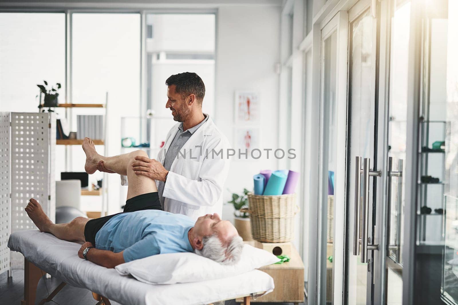 Assessing his range of movement. a young male physiotherapist assisting a senior patient in recovery. by YuriArcurs