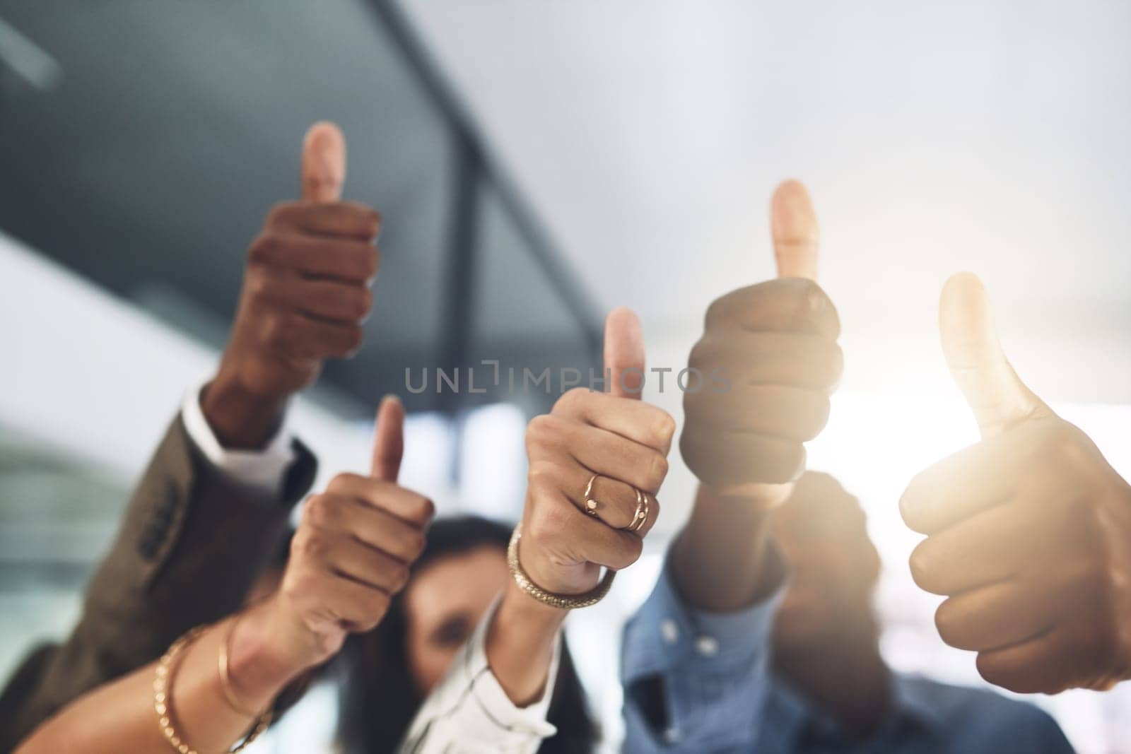 You should be proud of your achievements. Closeup shot of a group of businesspeople showing thumbs up in an office. by YuriArcurs