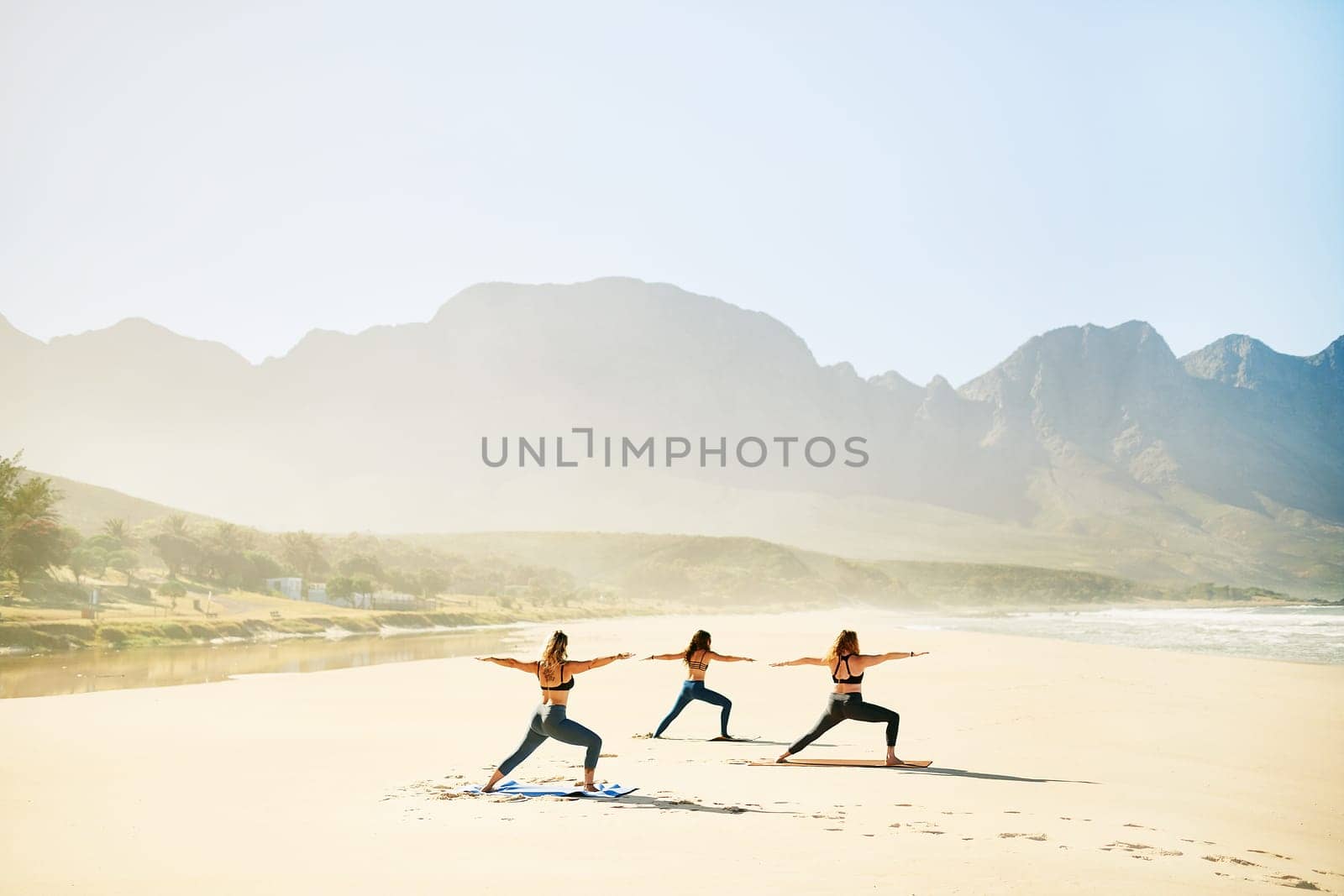 Be a warrior not a worrier. three young women practicing yoga on the beach