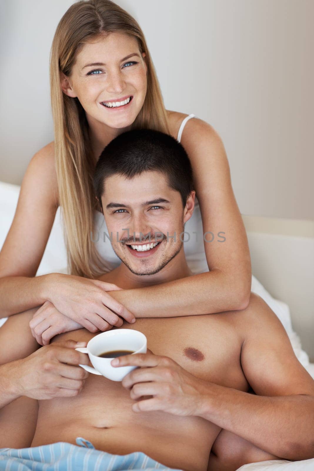 Theres no better way to enjoy a cup. Handsome young man enjoying some coffee in bed while relaxing with his partner