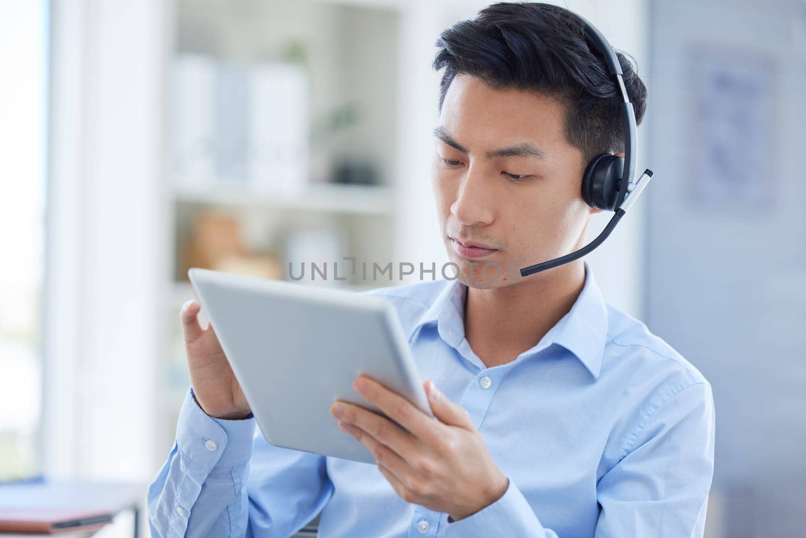 Call center, tablet and focus with asian man in office for consulting, customer service and contact us. Communication, focus and help desk with male employee for technology, digital and networking by YuriArcurs
