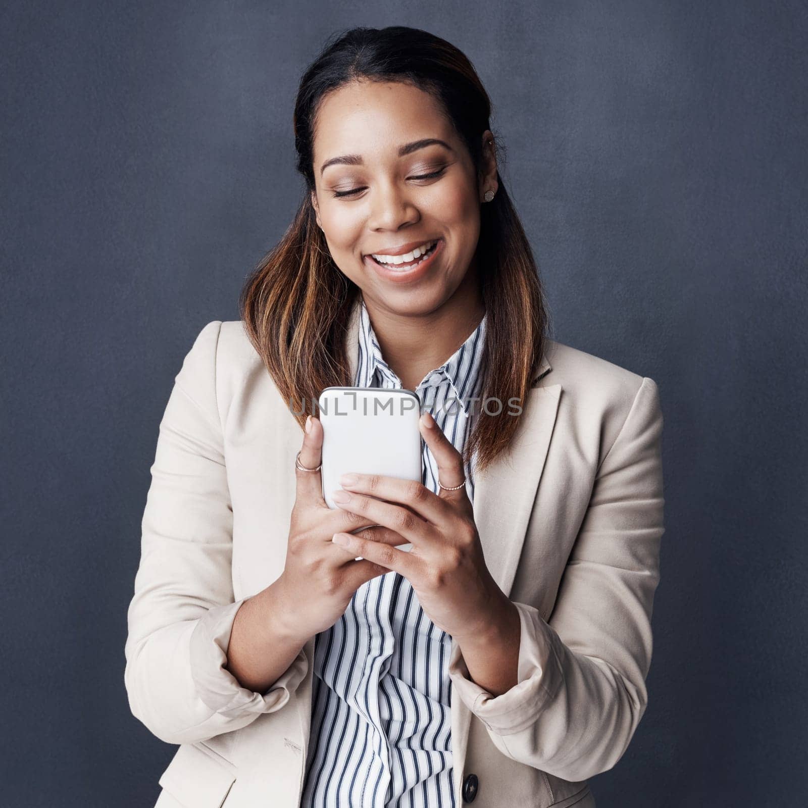 The perfect score is always something to strive for. Studio shot of a young businesswoman using her cellphone against a grey background. by YuriArcurs
