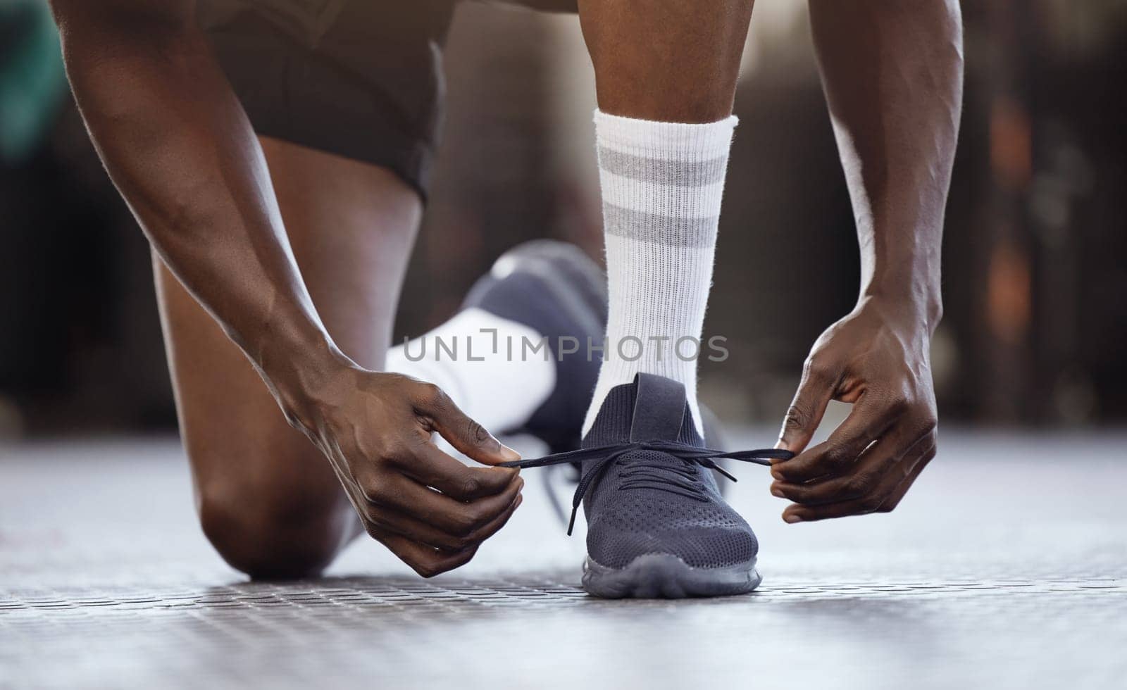 Tie, fitness and hands on shoes at gym for workout, training or exercise or runner ready to start exercising. Black man, goals and tie running shoes in sports performance, health practice or class.