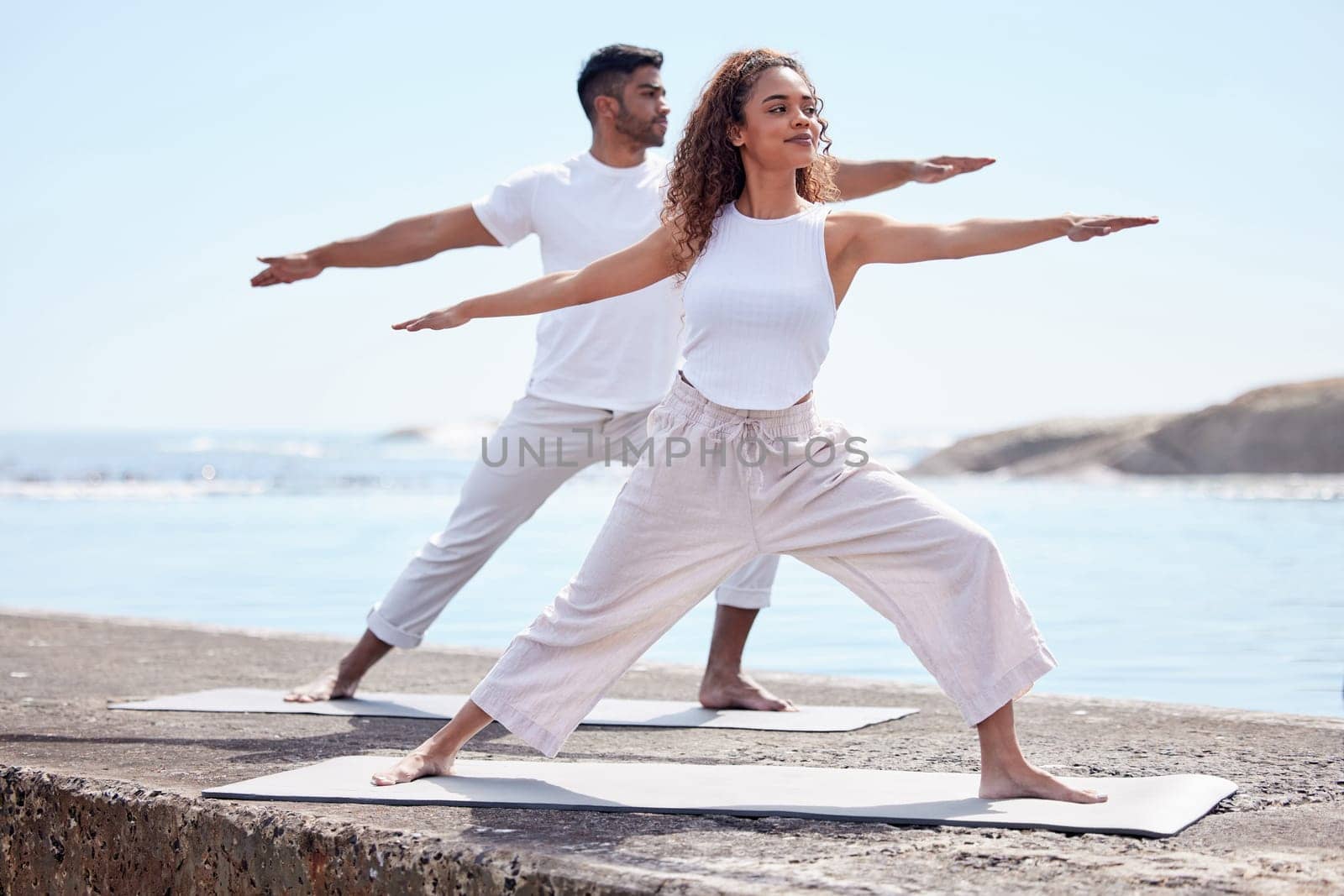 Couple yoga, beach and exercise outdoor in nature for fitness workout and wellness. African woman and a man at ocean for warrior pose, stretching or pilates training for peace, freedom or mindfulness.