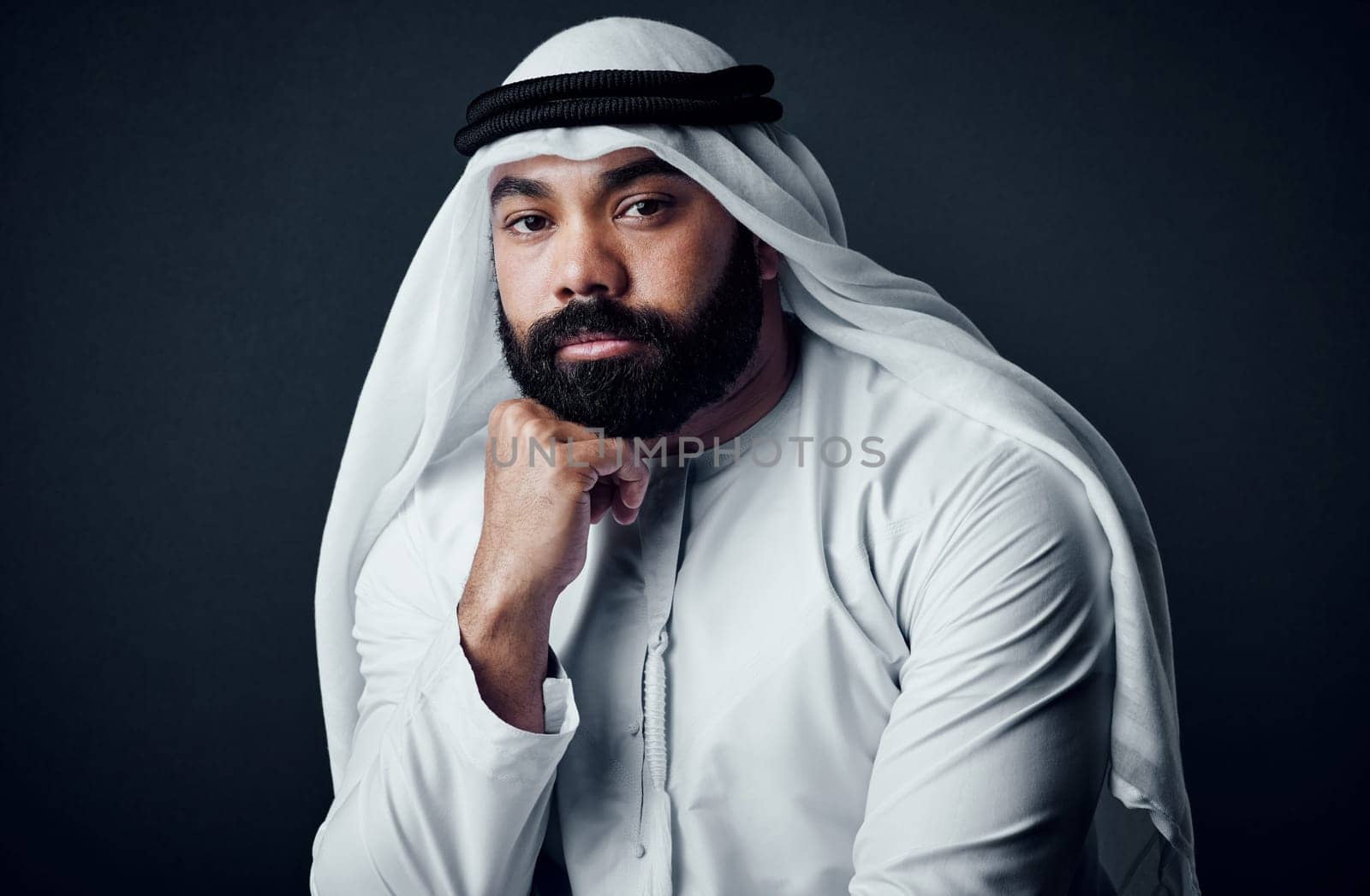 Attitude of a champion. Studio shot of a young man dressed in Islamic traditional clothing posing against a dark background. by YuriArcurs