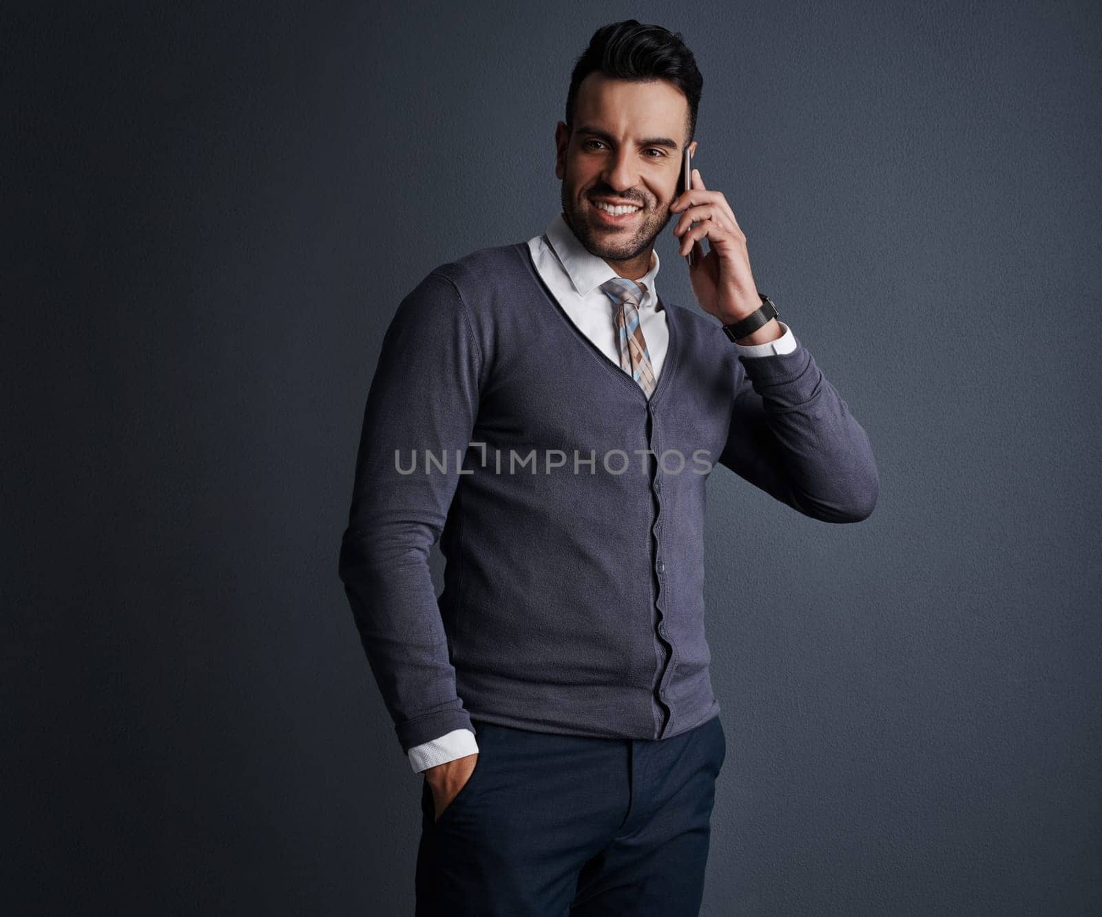 Hes perfected the art of business communication. Studio shot of a stylish young businessman using a mobile phone against a gray background. by YuriArcurs